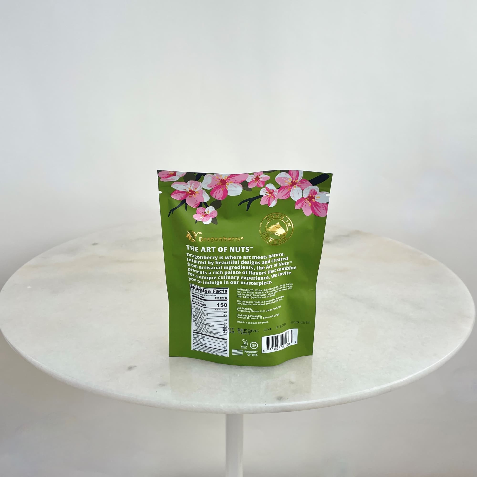 Green snack pouch with pink cherry blossom graphics on a white table