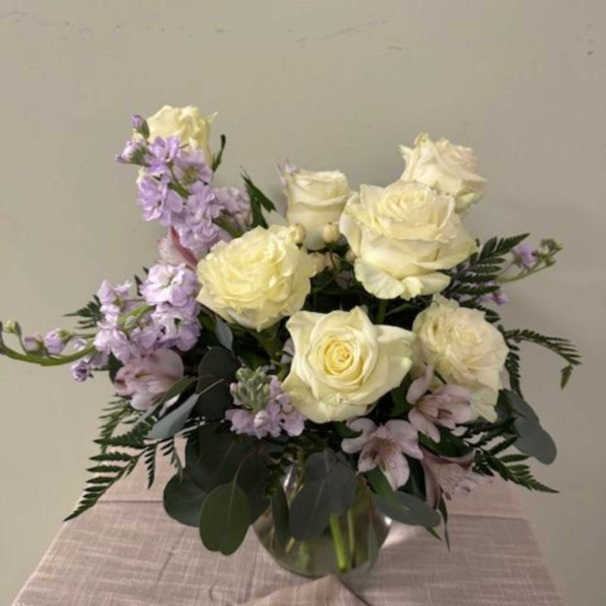 White roses and lavender flowers arranged in a glass vase
