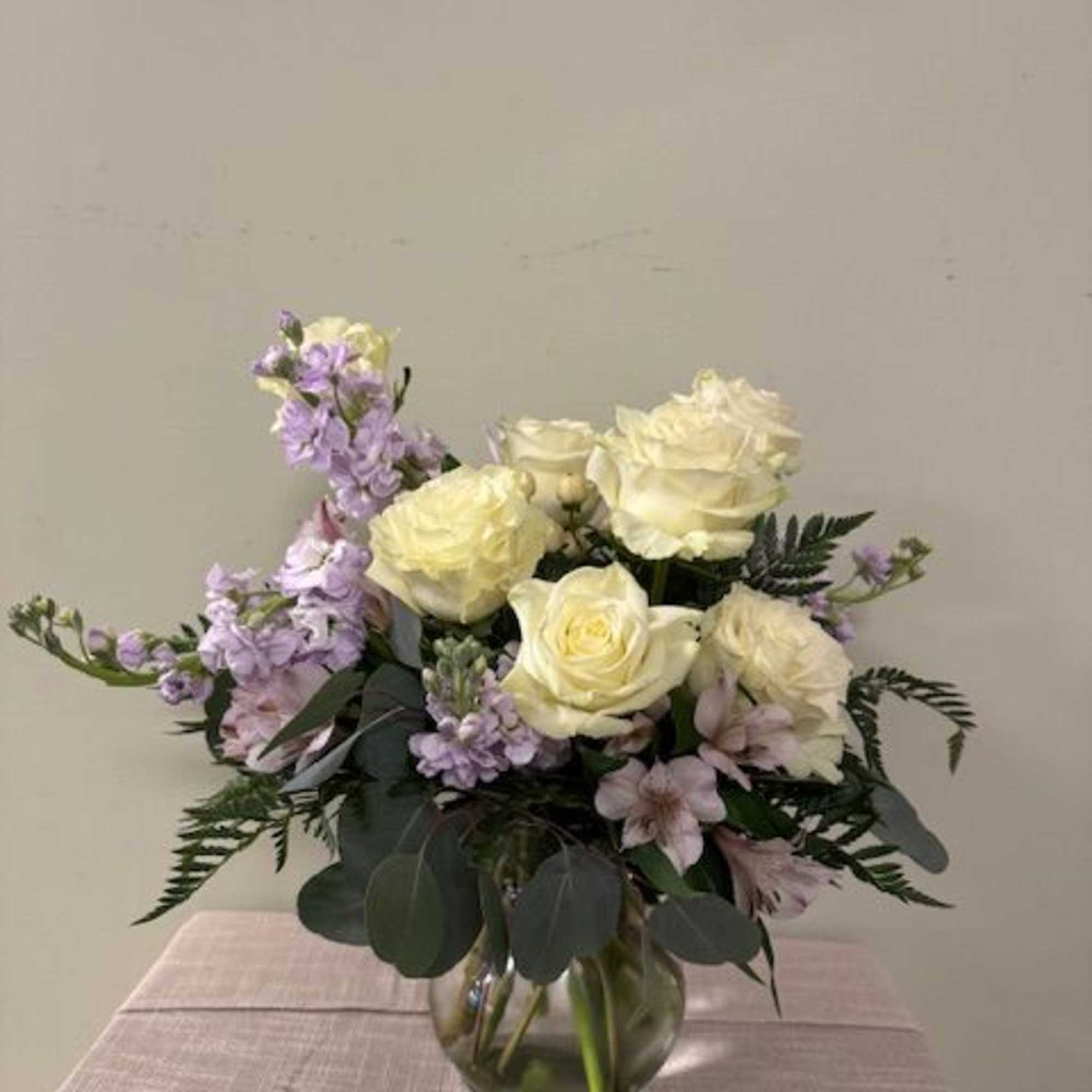 White roses and lavender flowers arranged in a glass vase