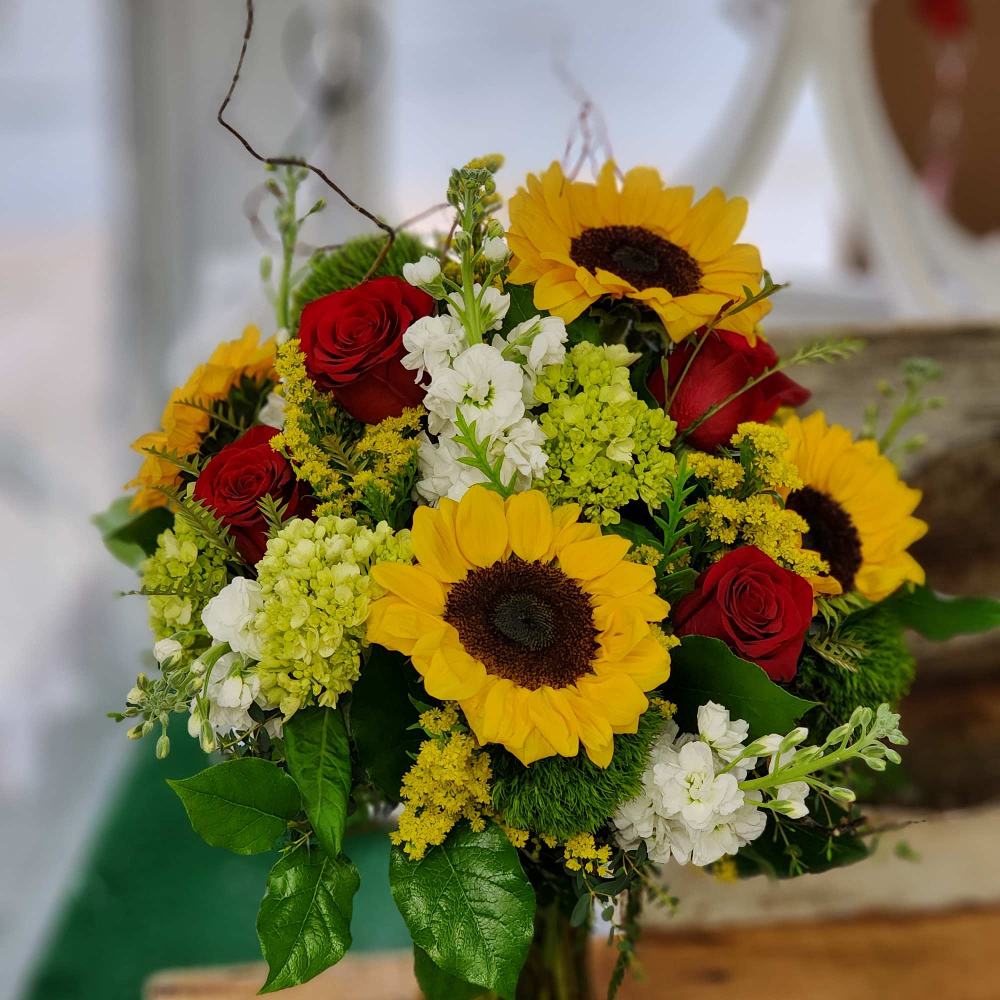 Bouquet of red roses and yellow sunflowers in a glass vase