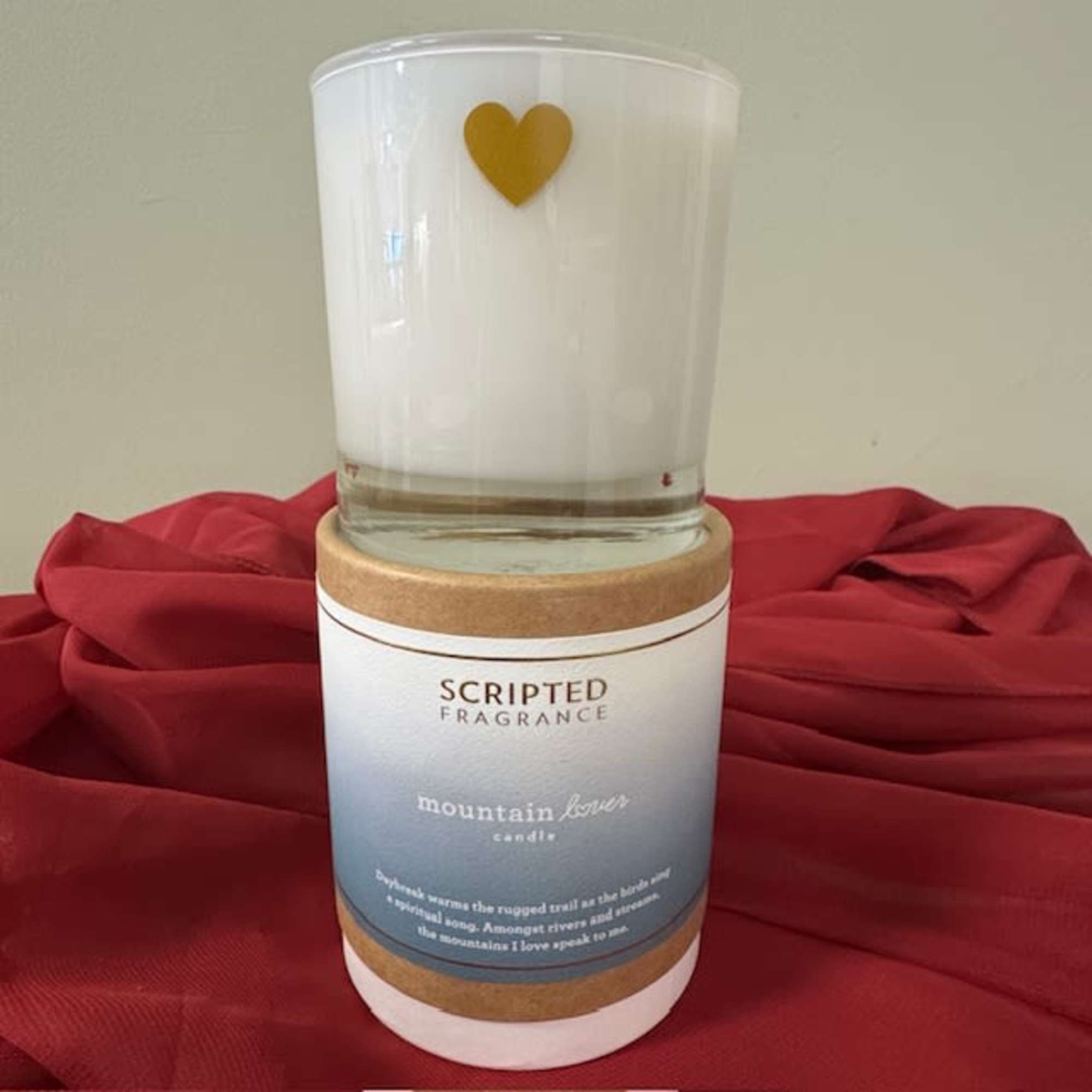 White candle in a glass jar with a gold heart on the front