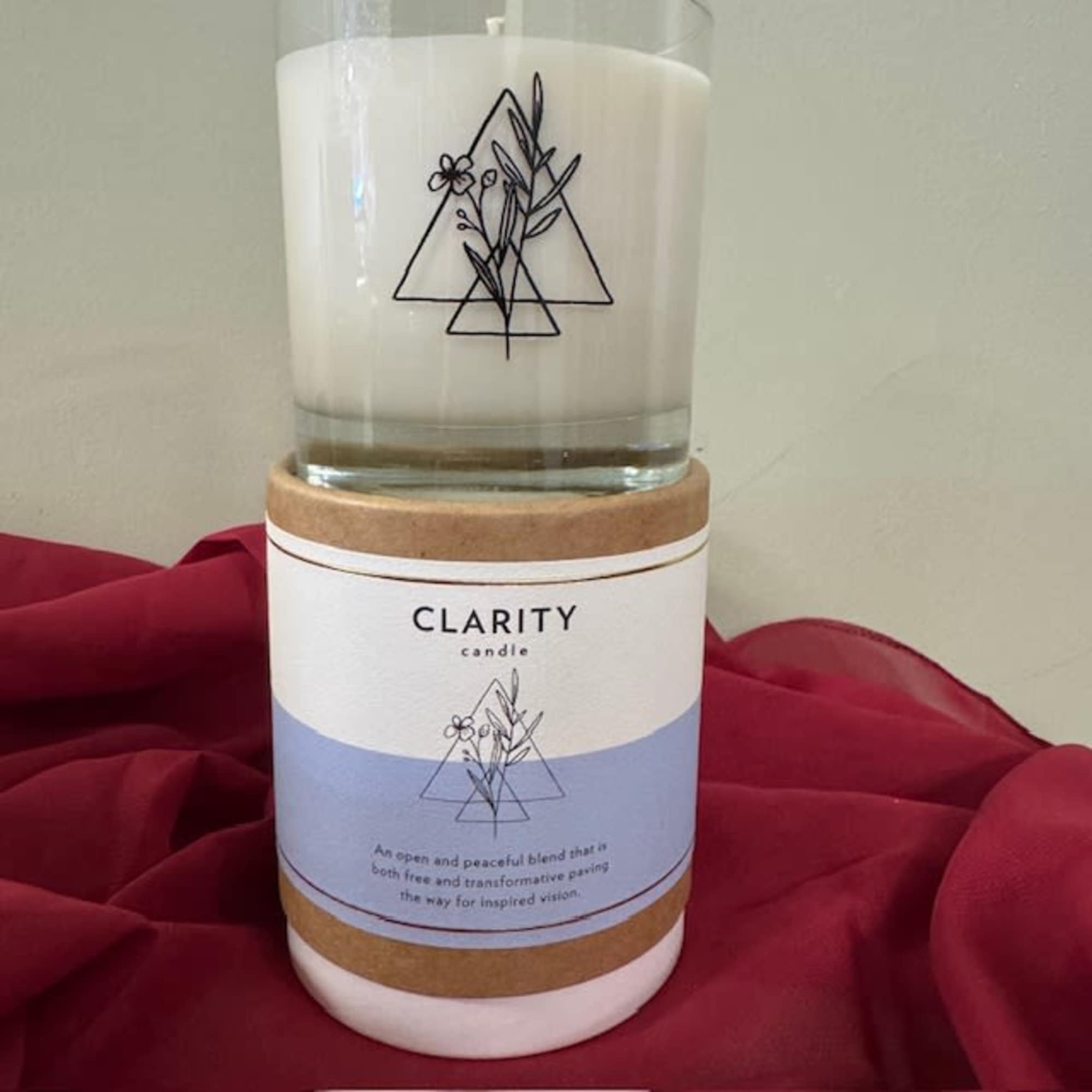 A white candle in a glass jar with a cork lid and label.