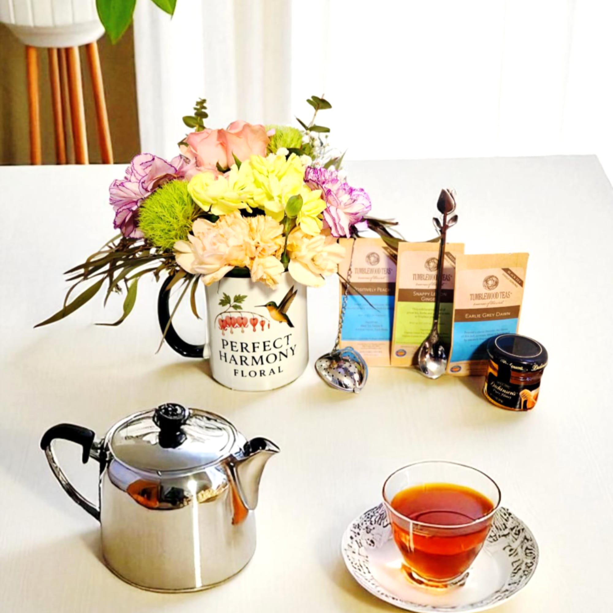 Flower arrangement in a mug with tea bags, teapot, and a cup of tea