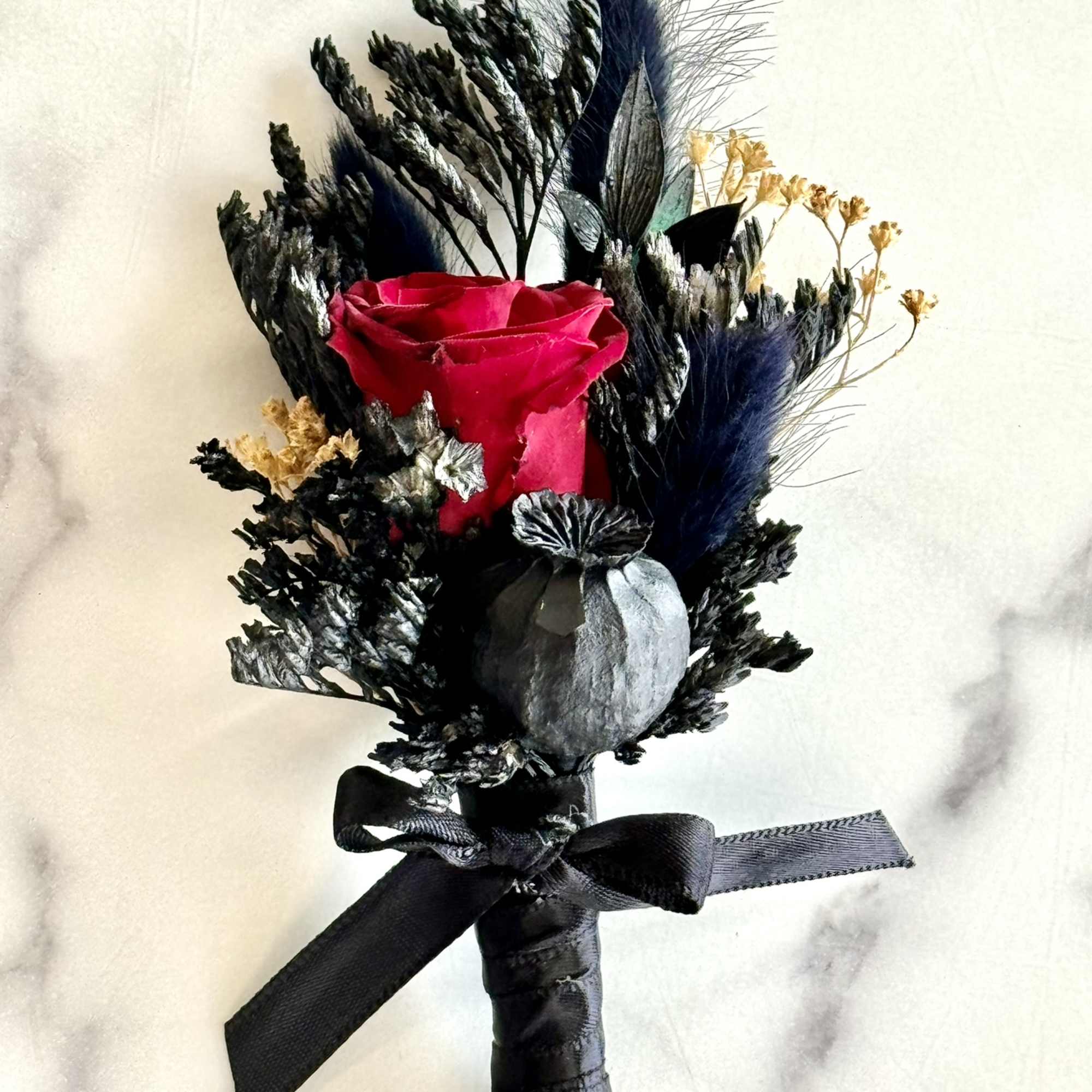 Single red rose boutonniere with dark dried accents and black ribbon