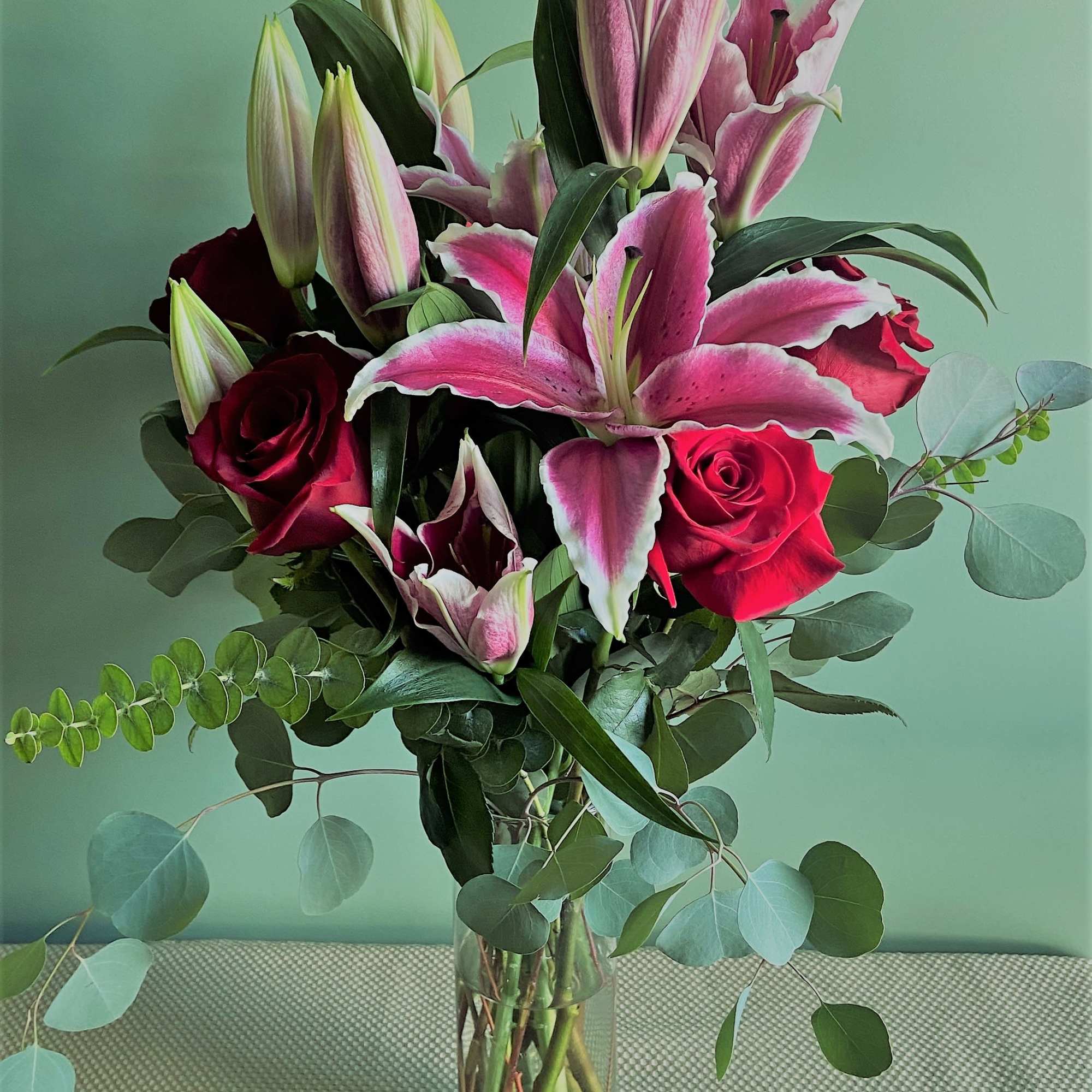 Bouquet of pink lilies and red roses in a clear glass vase