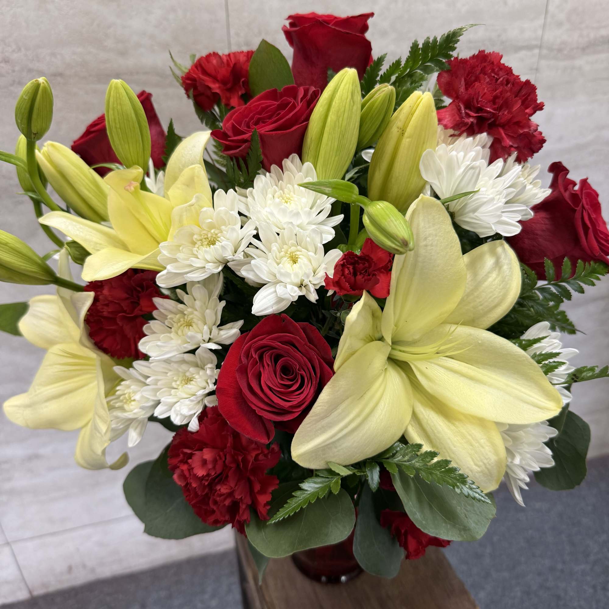 Bouquet of red roses, yellow lilies, white daisies, and red carnations in a vase