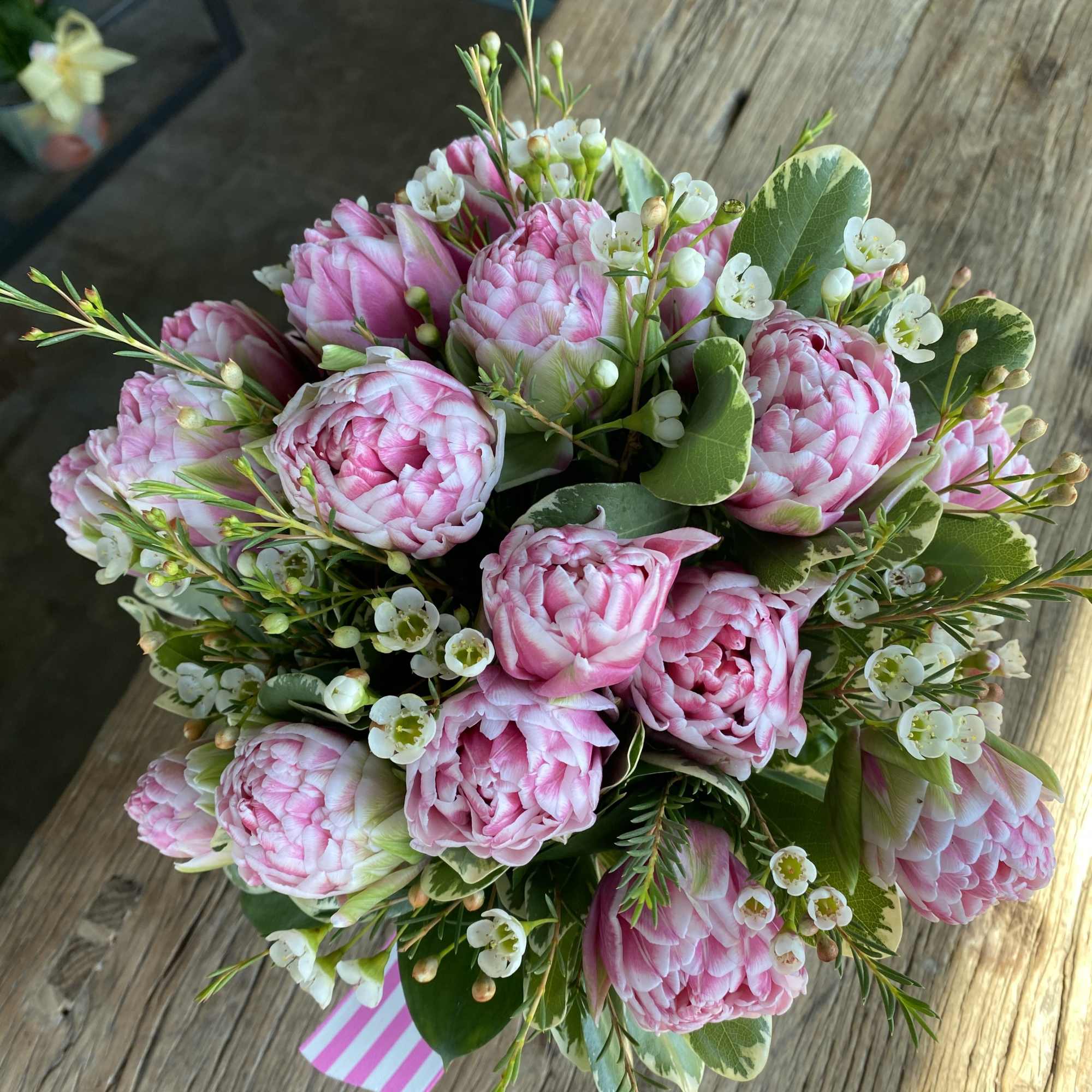 Pink ranunculus bouquet with small white blossoms and greenery