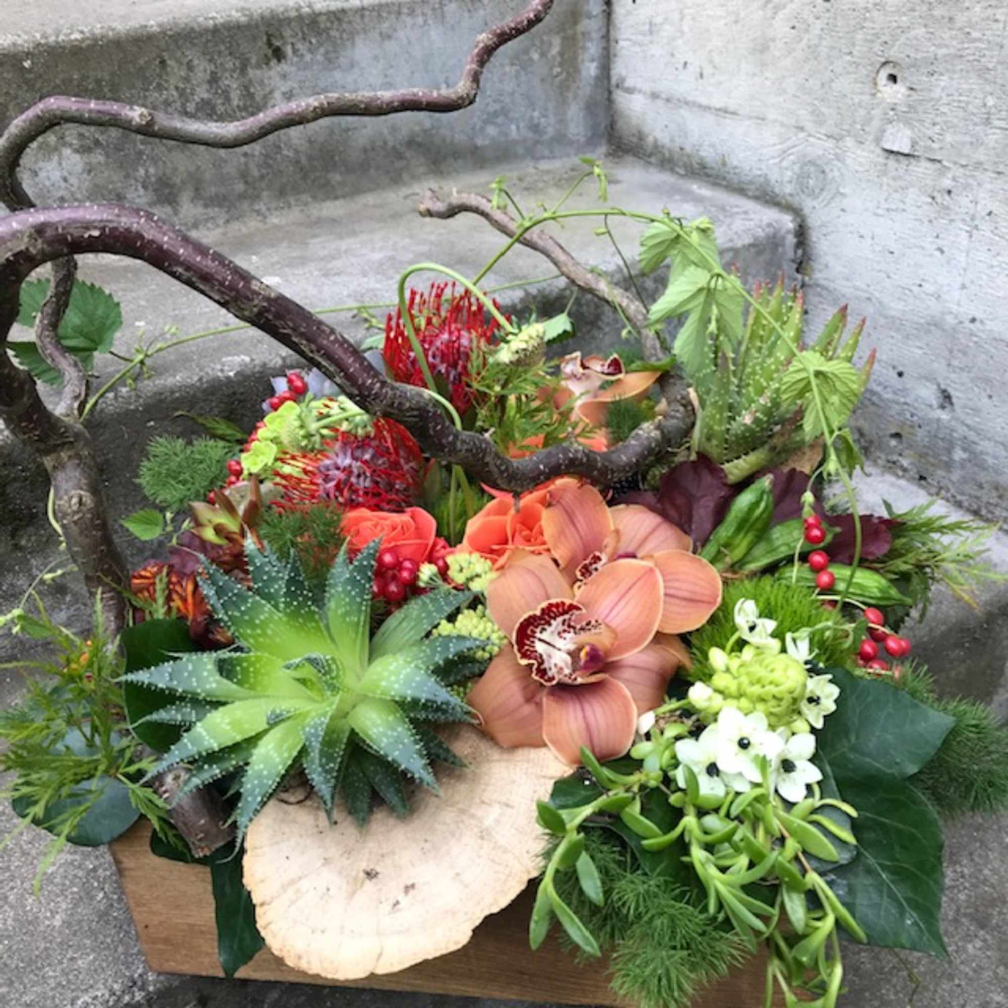 Tropical floral arrangement with orchids and succulents in a wooden box