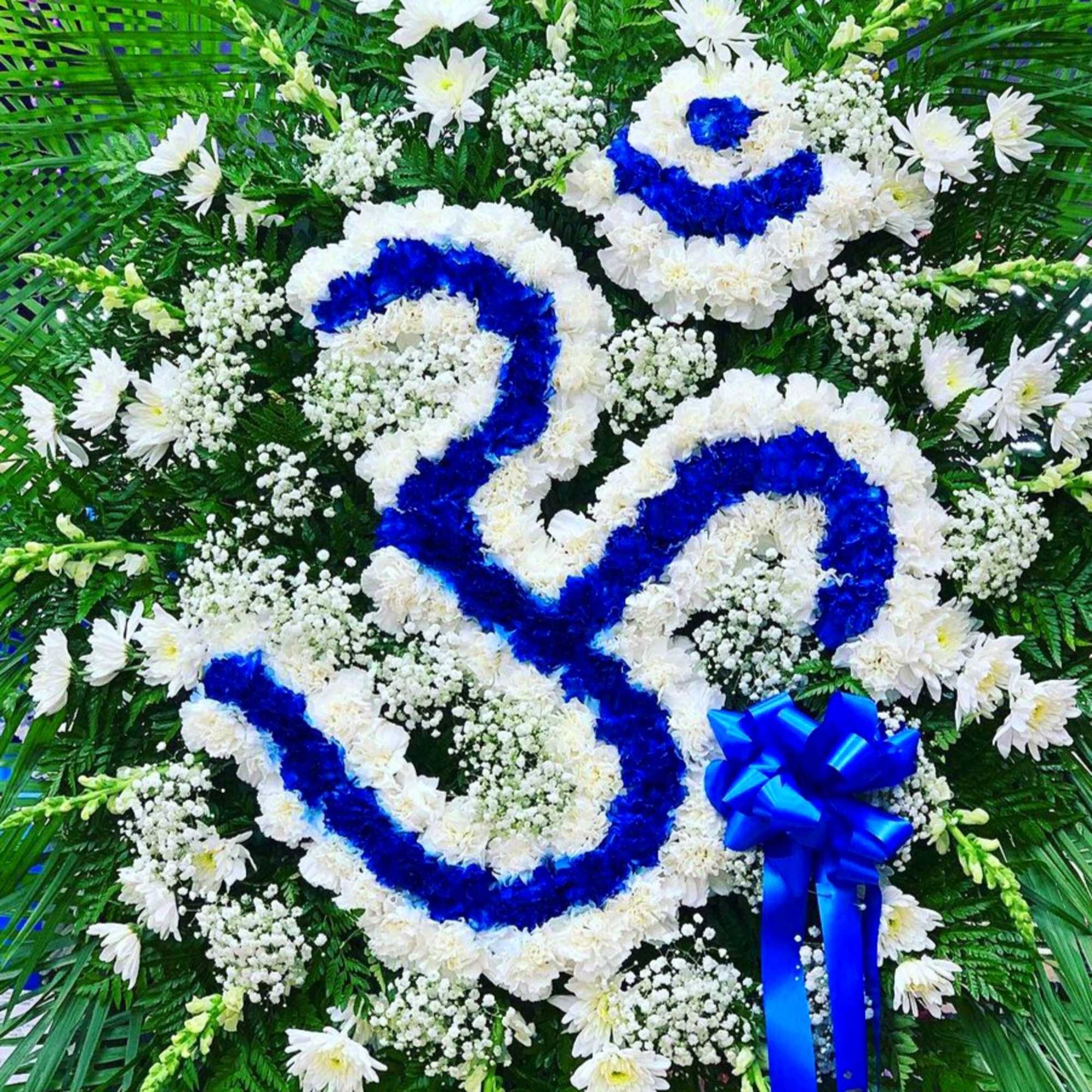 White floral funeral wreath with blue ribbon accents