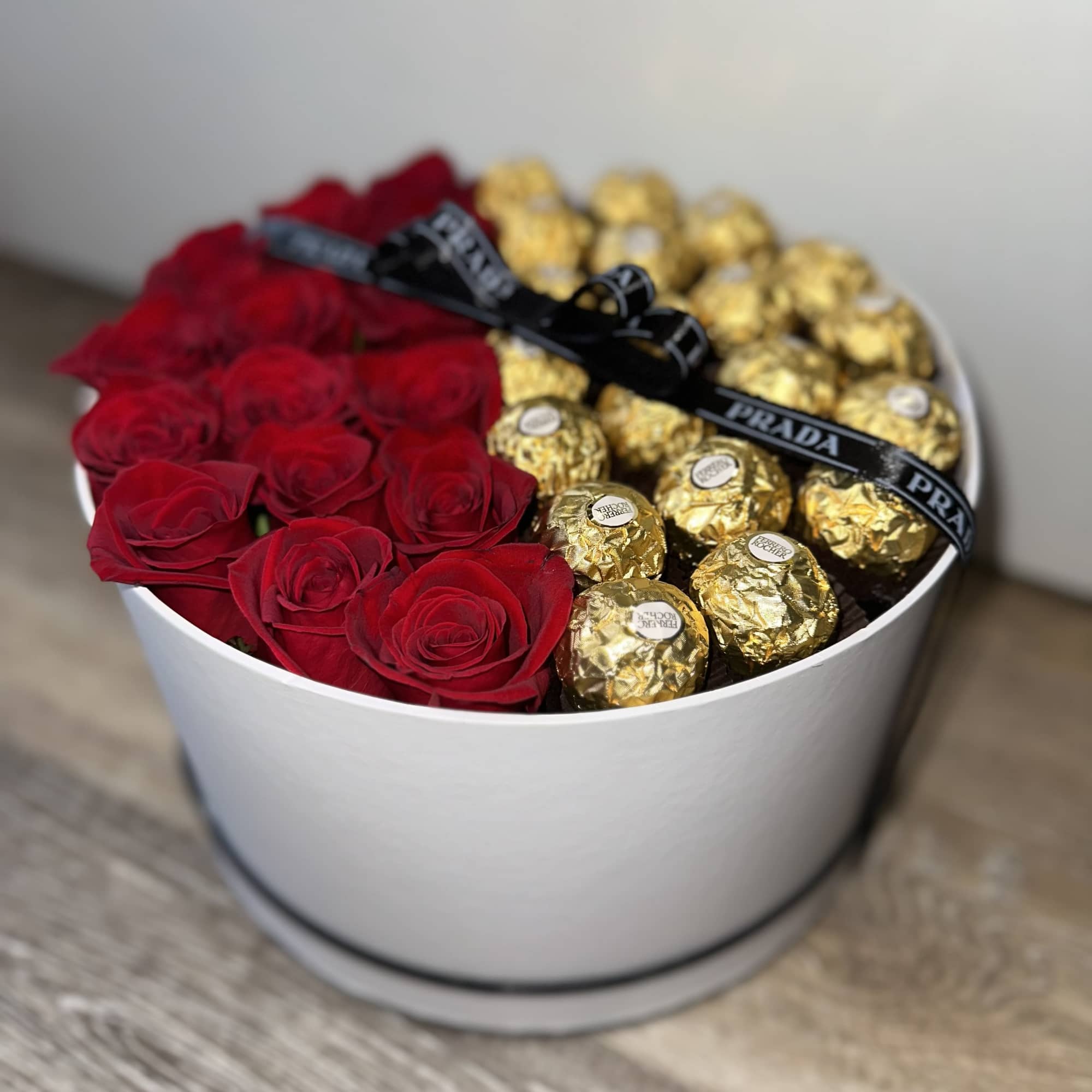 Red roses and gold-wrapped chocolates arranged in a white round box