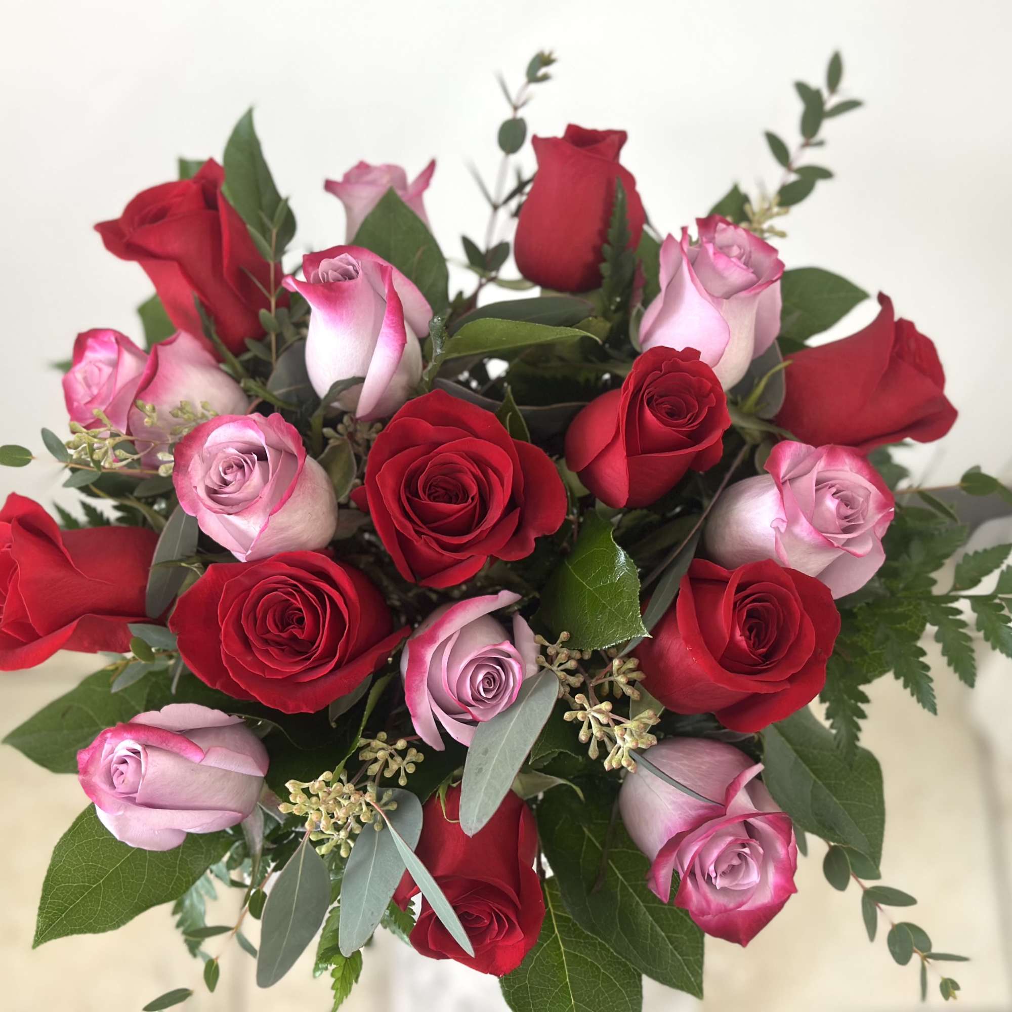Bouquet of red and pink roses with mixed greenery