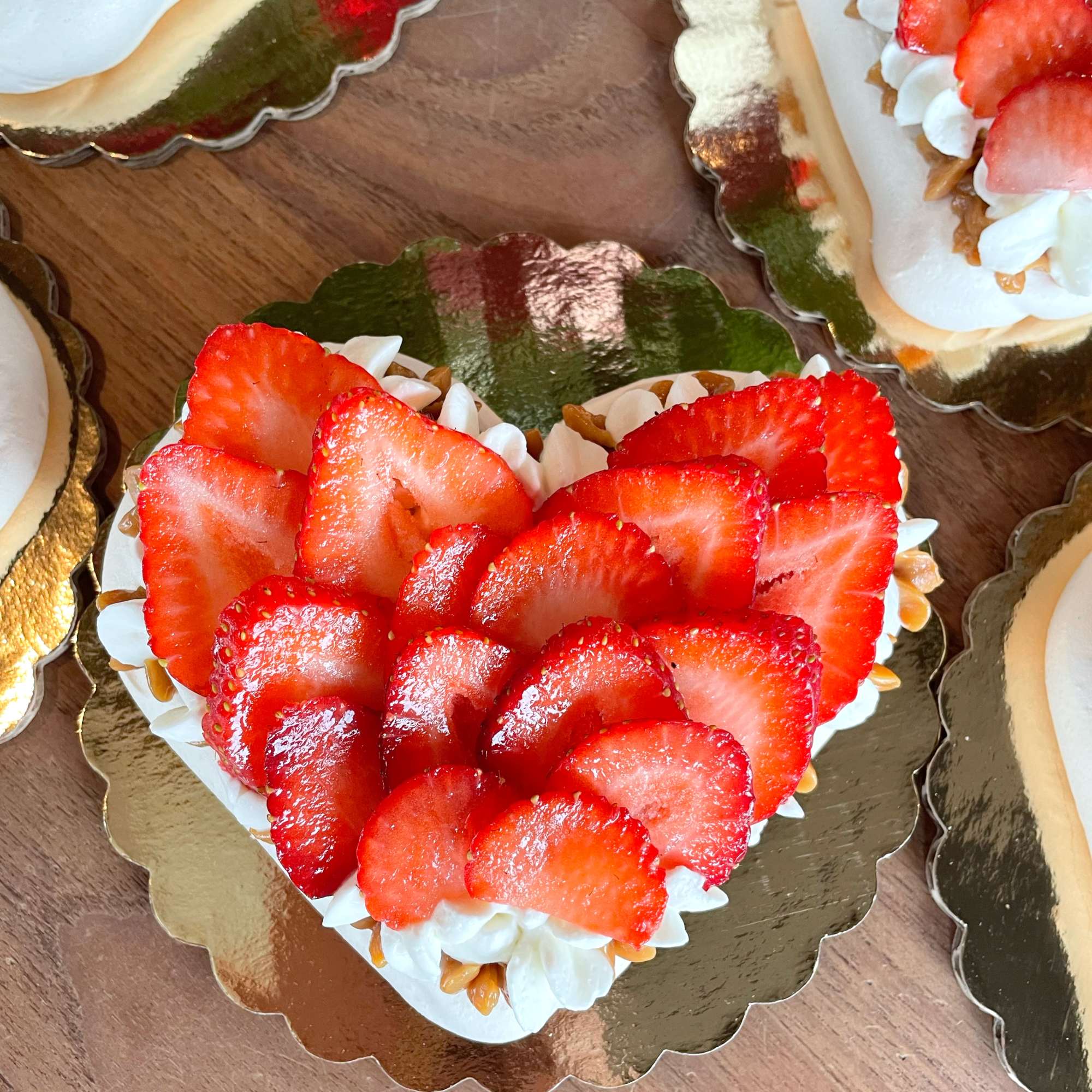Heart-shaped dessert topped with sliced strawberries on a gold board