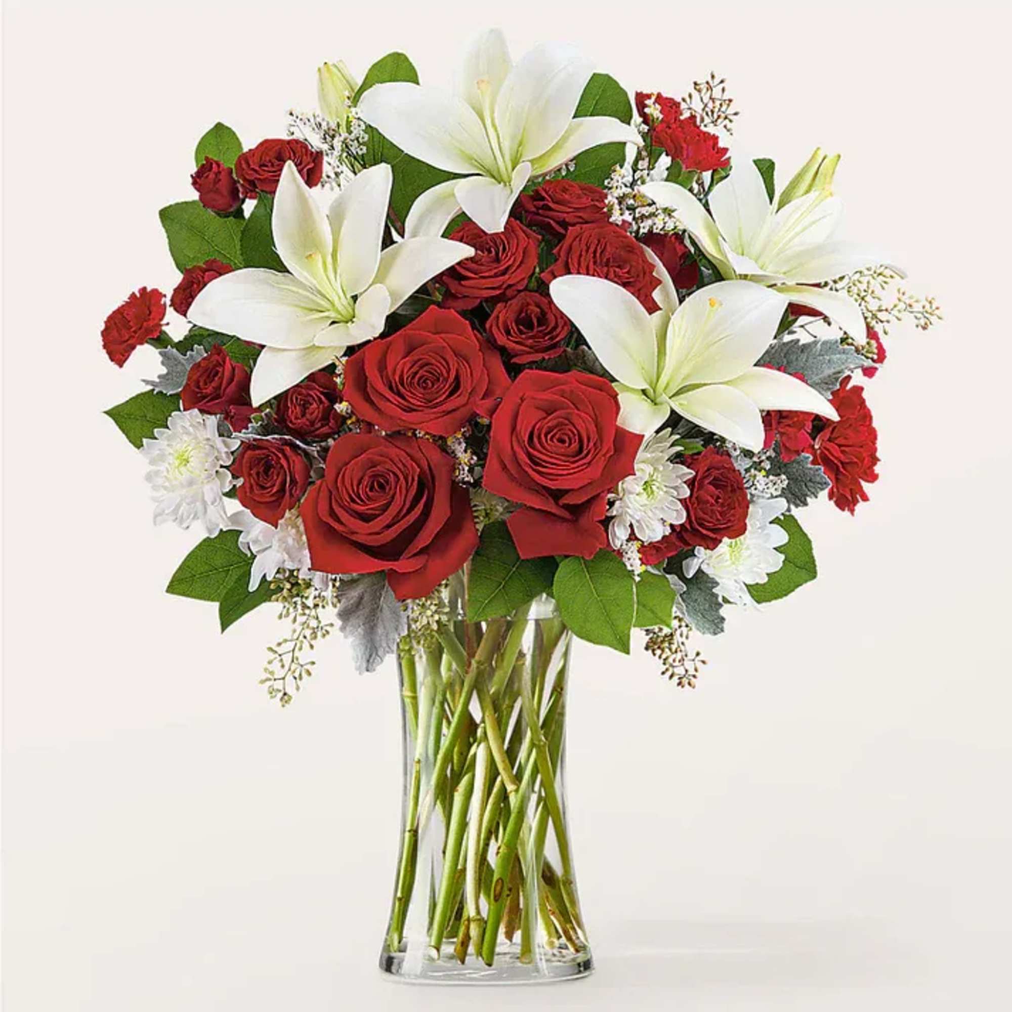 Red roses and white lilies arranged in a clear glass vase.