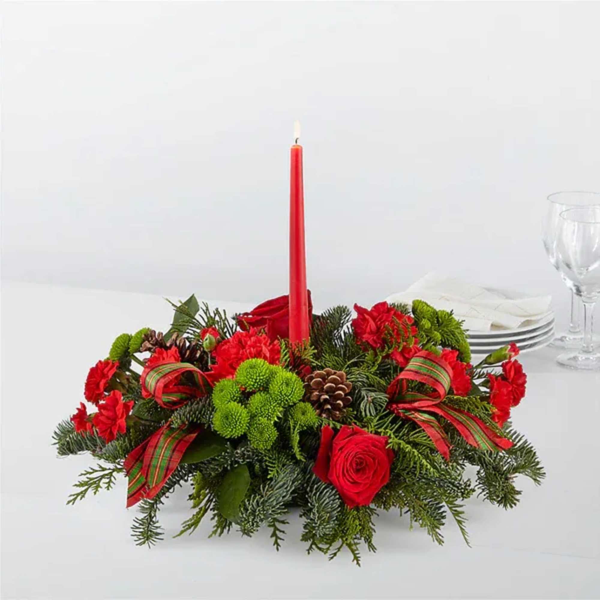 Red floral centerpiece with a tall candle and ribbon accents