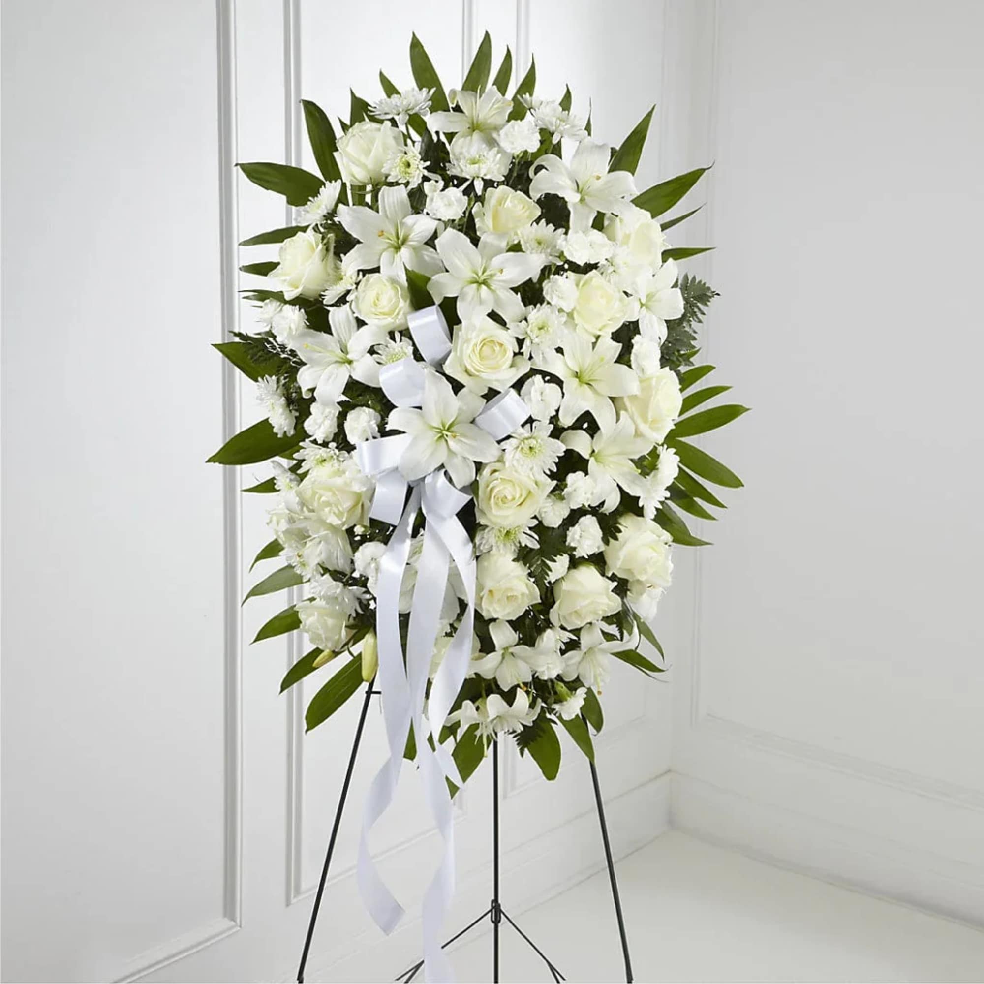 White floral standing spray on an easel with a ribbon