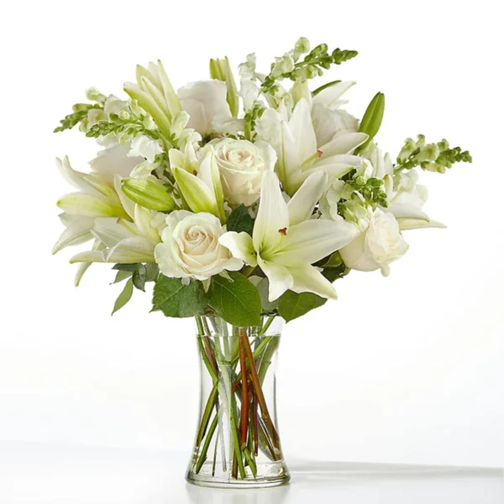 White lilies and roses arranged in a clear glass vase