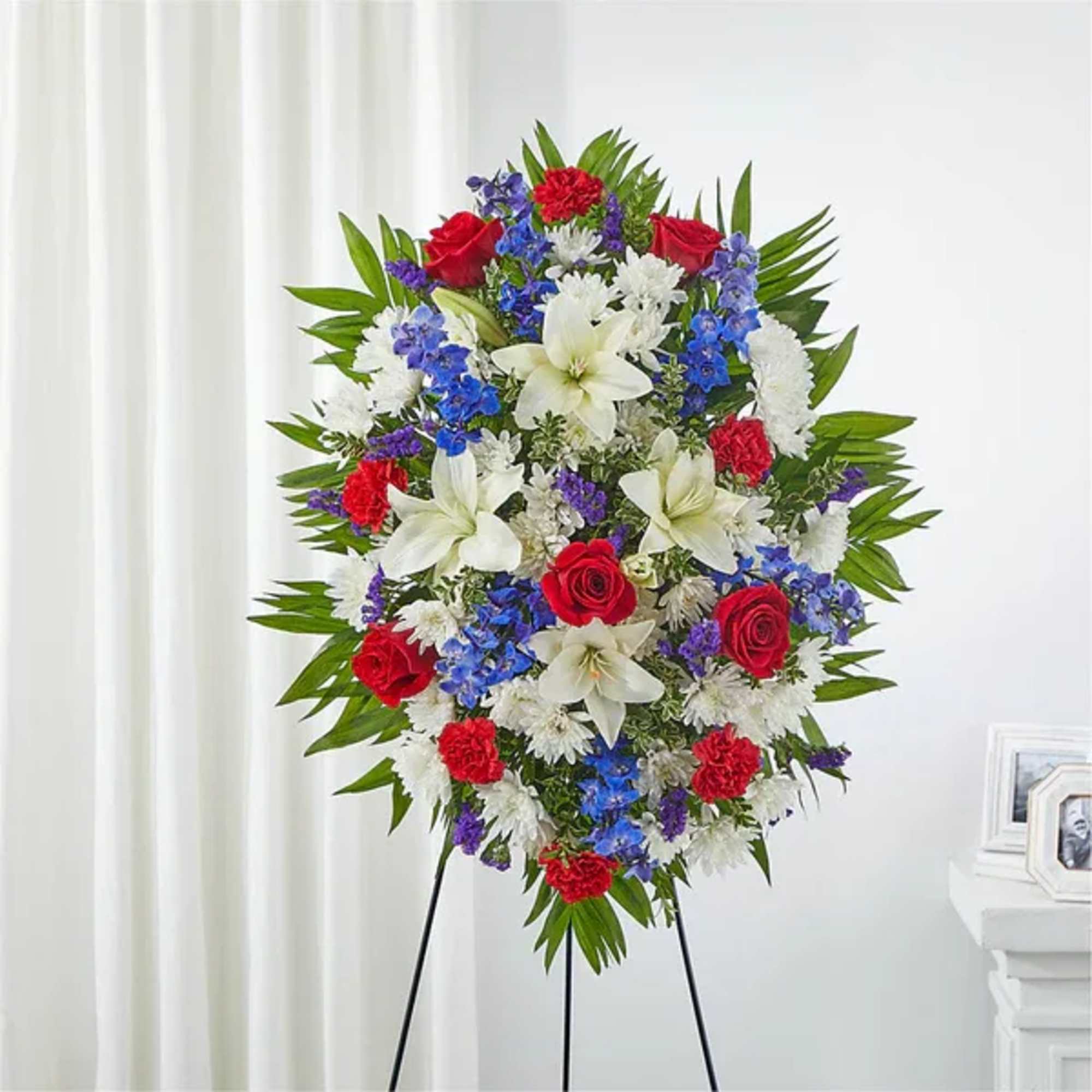 Standing floral spray with red, white, and blue flowers on an easel