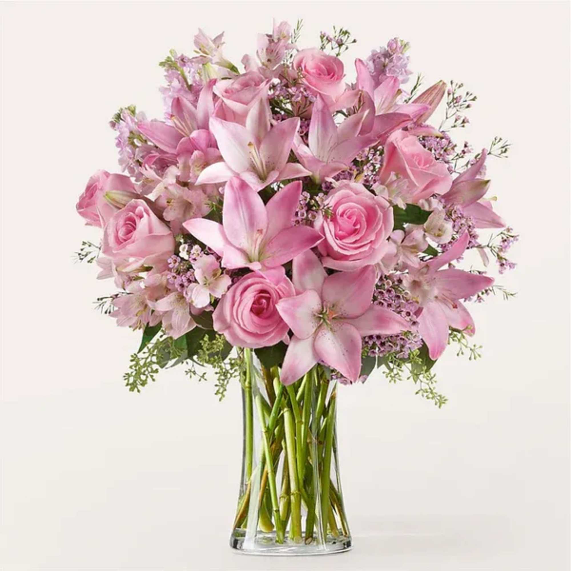 Pink roses and lilies arranged in a clear glass vase