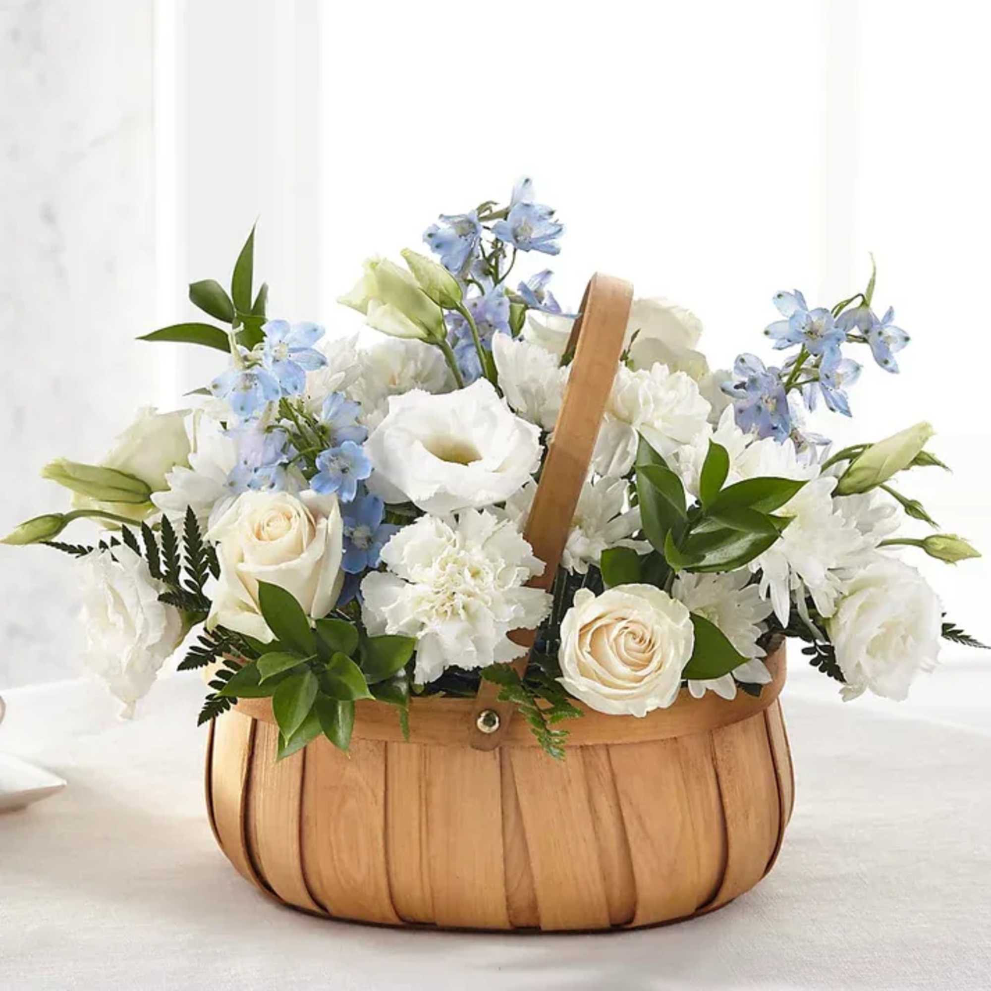 Basket of white flowers with pale blue blooms and greenery