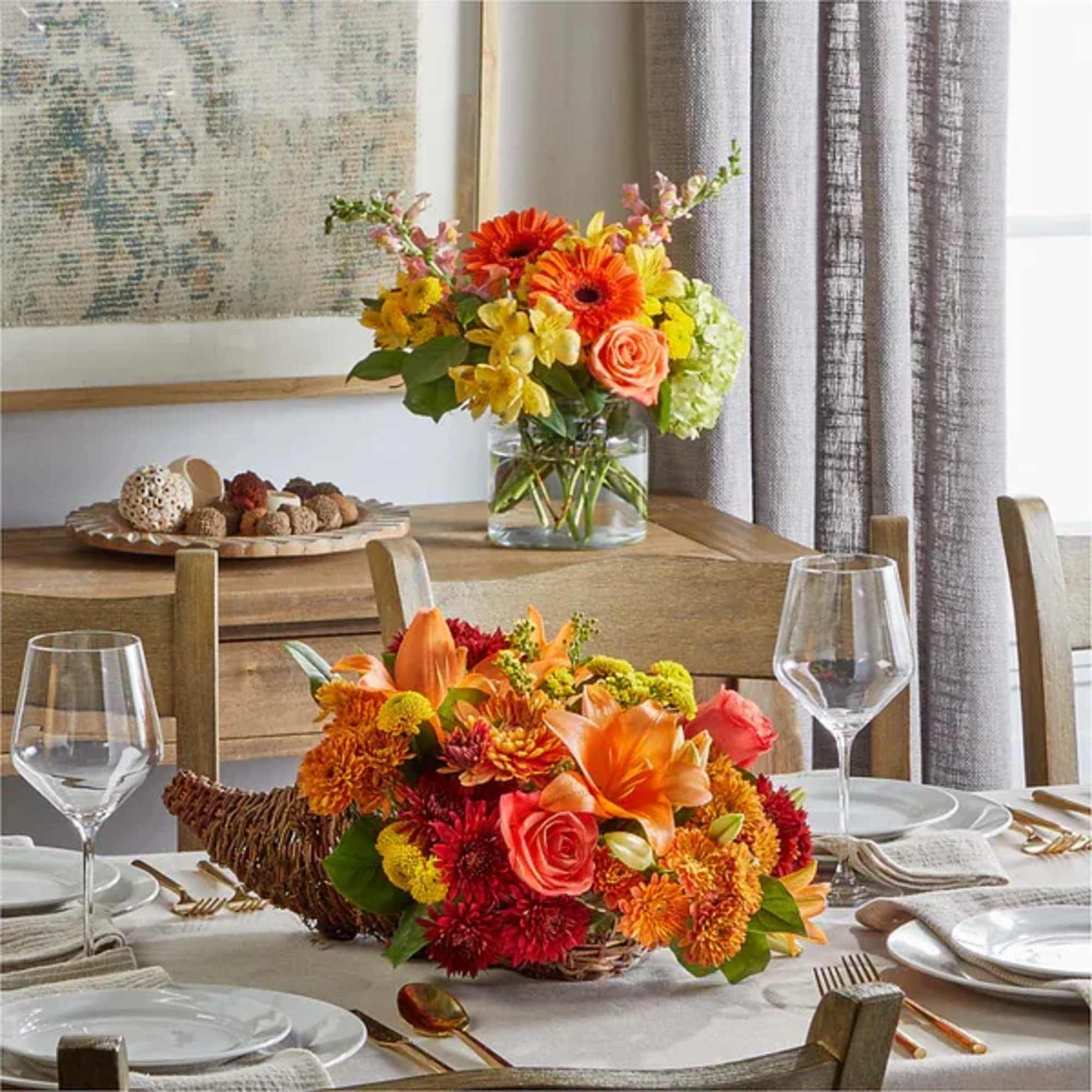 Two colorful floral centerpieces in glass and woven containers on a dining table