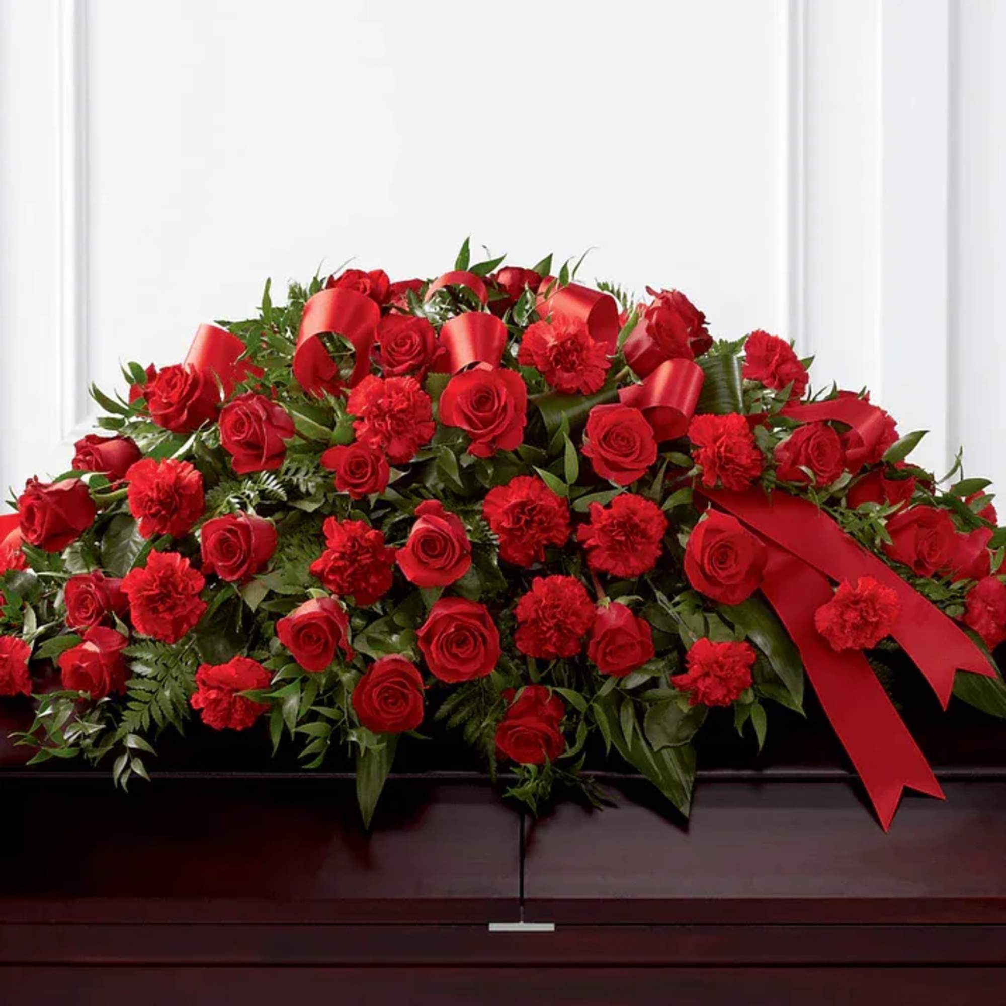Large red rose and carnation casket spray with ribbon accents