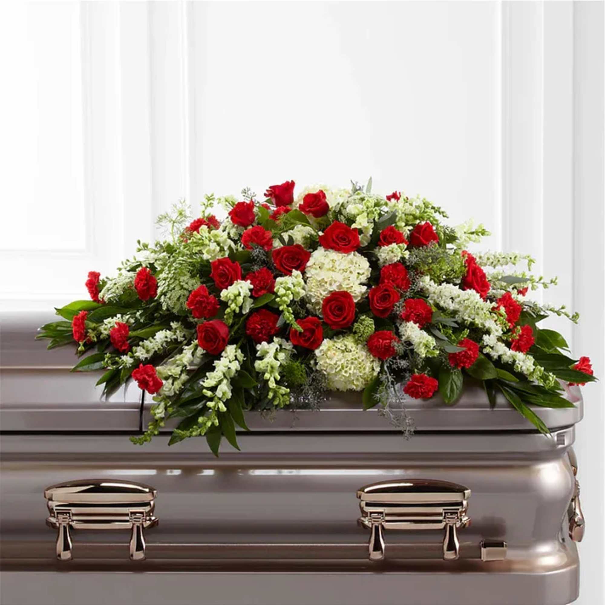 Red roses and white flowers arranged on a silver casket
