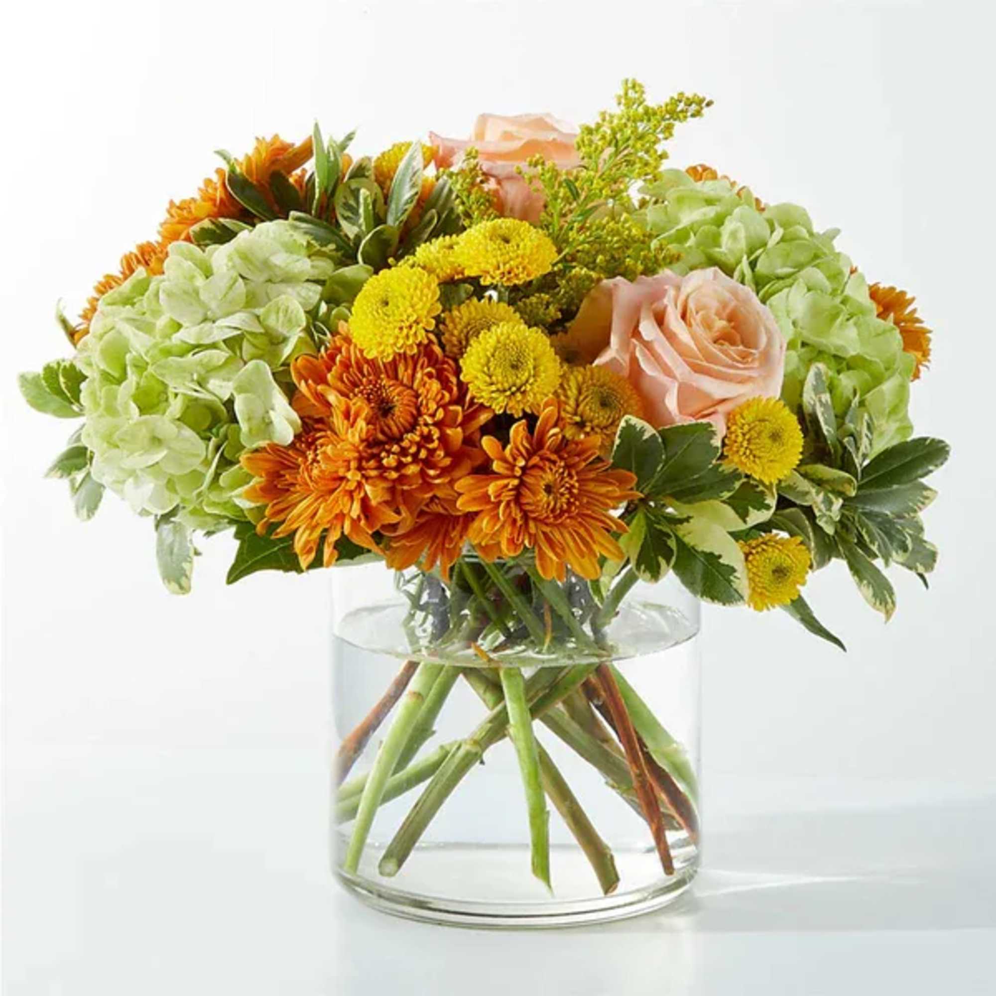 Bouquet of orange and yellow flowers with pale pink roses in a glass vase