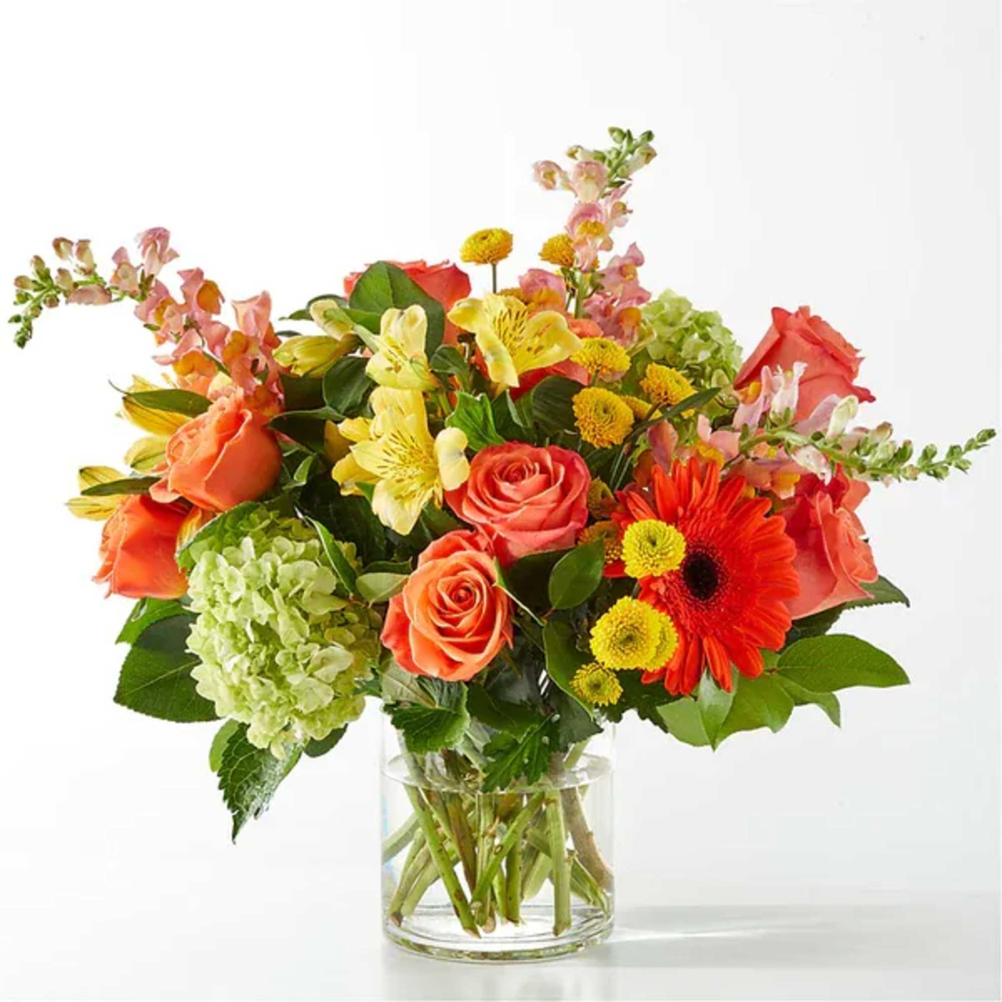 Mixed bouquet of orange roses, yellow lilies, and a red gerbera daisy in a glass vase