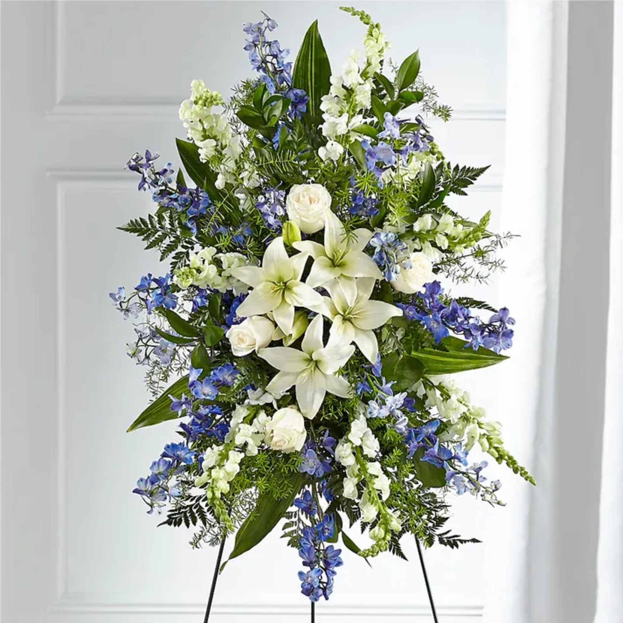 Tall white and blue floral standing spray on an easel