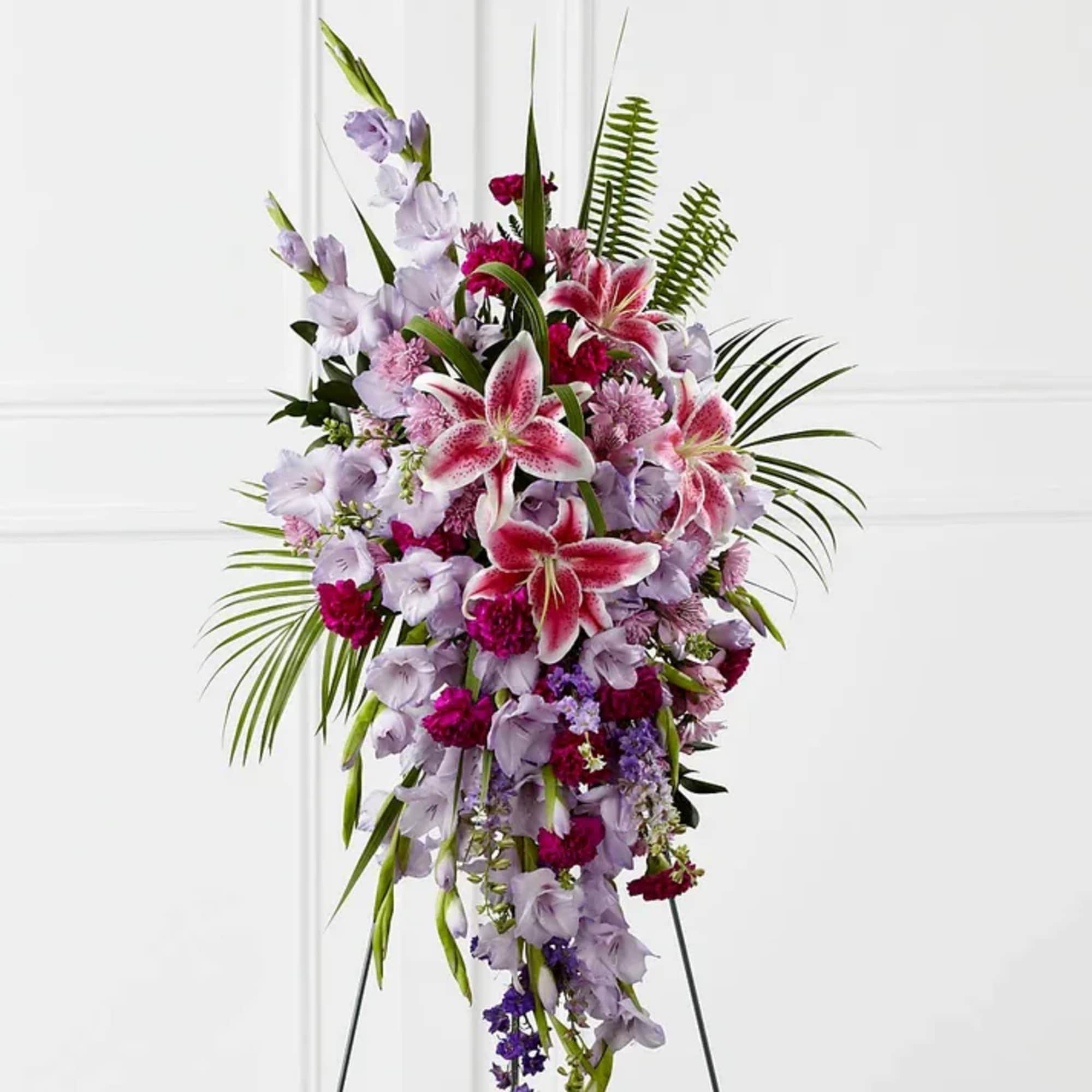 Tall standing spray of pink and lavender flowers with lilies and palm fronds