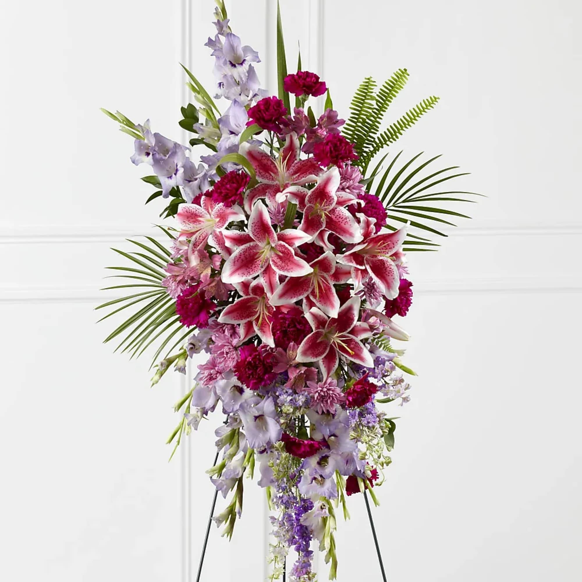 Tall standing spray of pink lilies and lavender flowers on a black easel