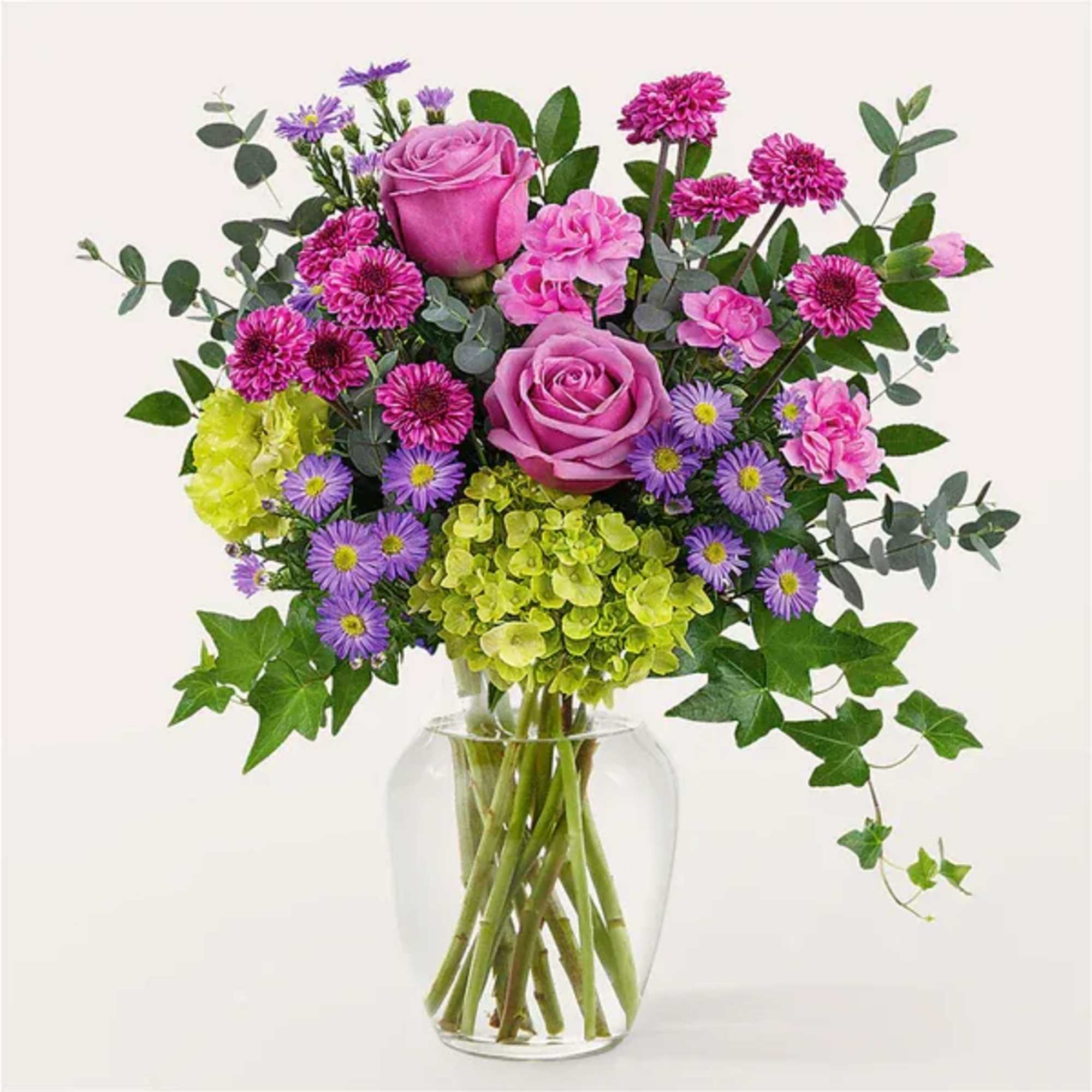 Pink roses and purple flowers in a clear glass vase