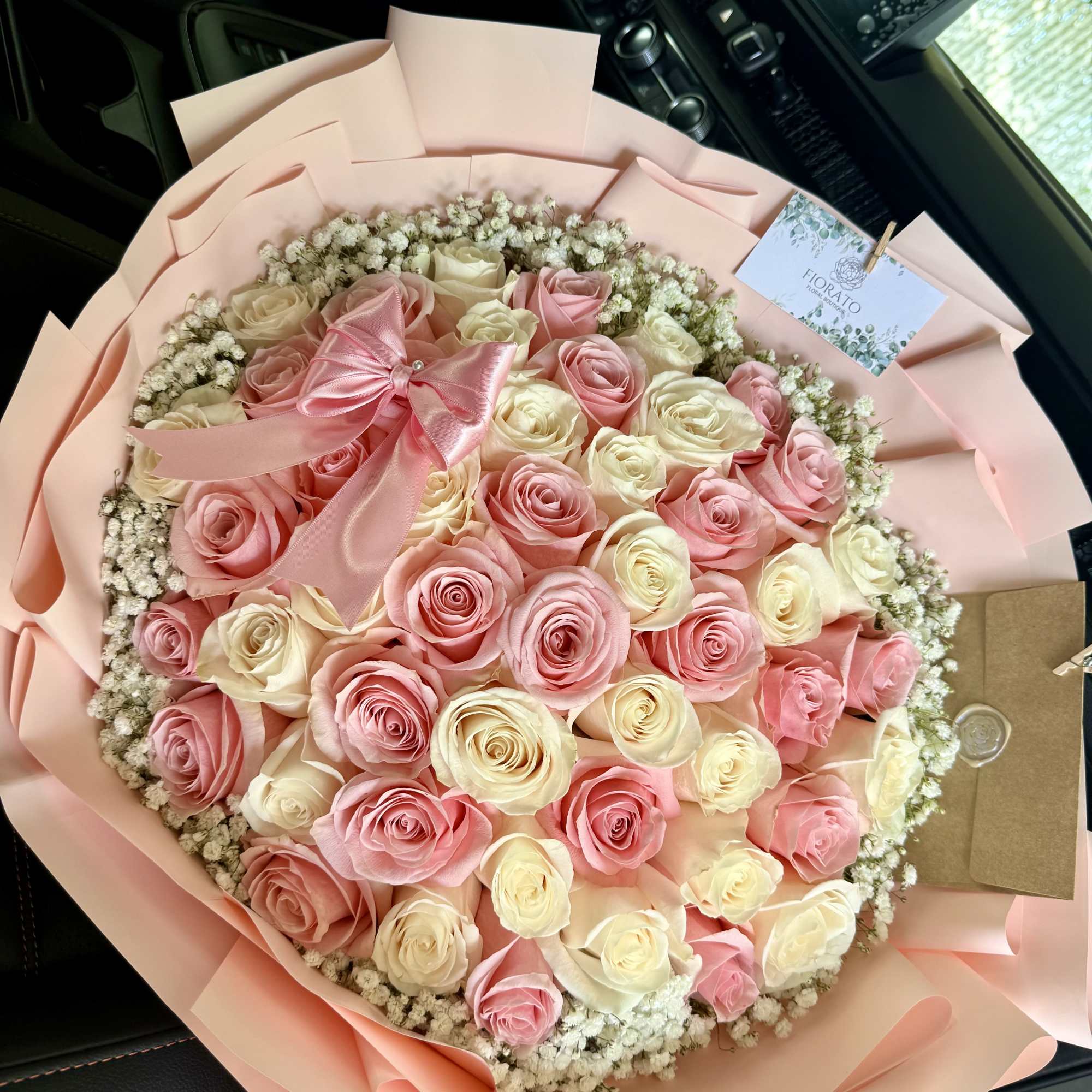 A lush, round bouquet of tightly packed pink and cream roses edged