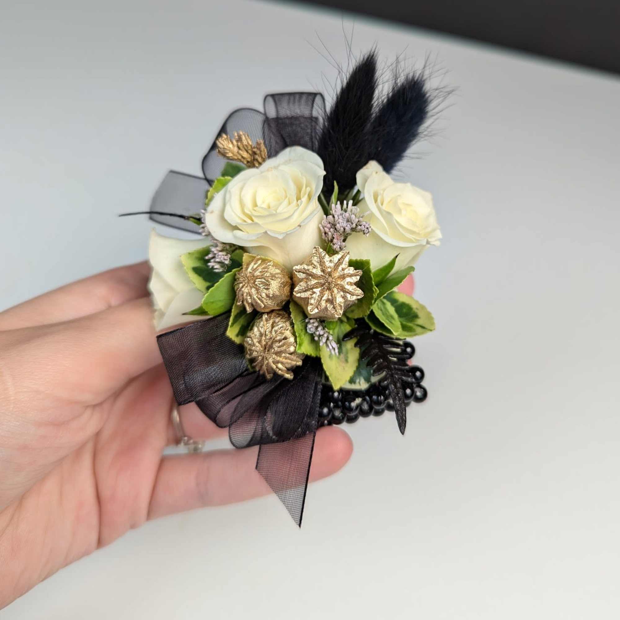 Small corsage with white roses, black ribbon, and gold accents