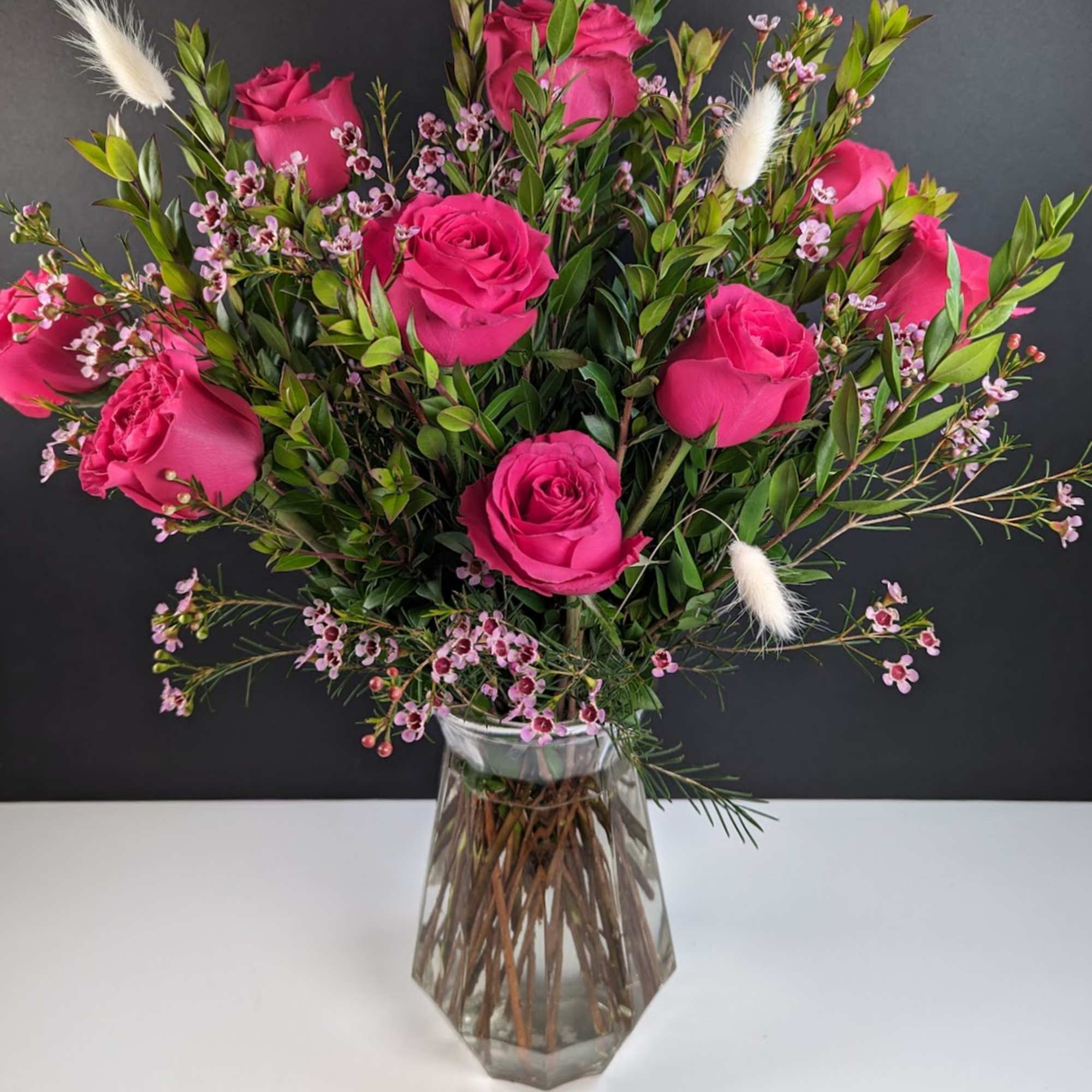 Pink roses arranged in a clear glass vase with small filler flowers