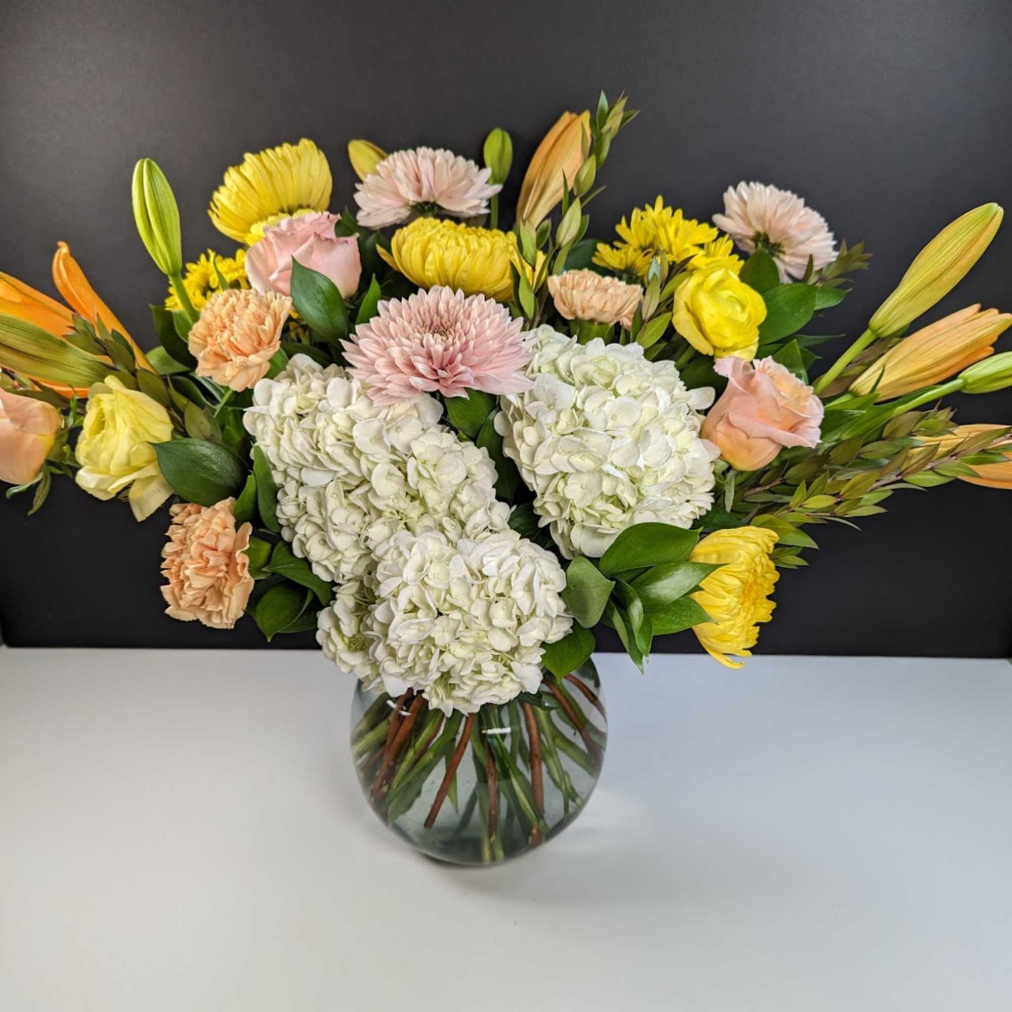 Mixed bouquet of hydrangeas, roses, and chrysanthemums in a glass vase
