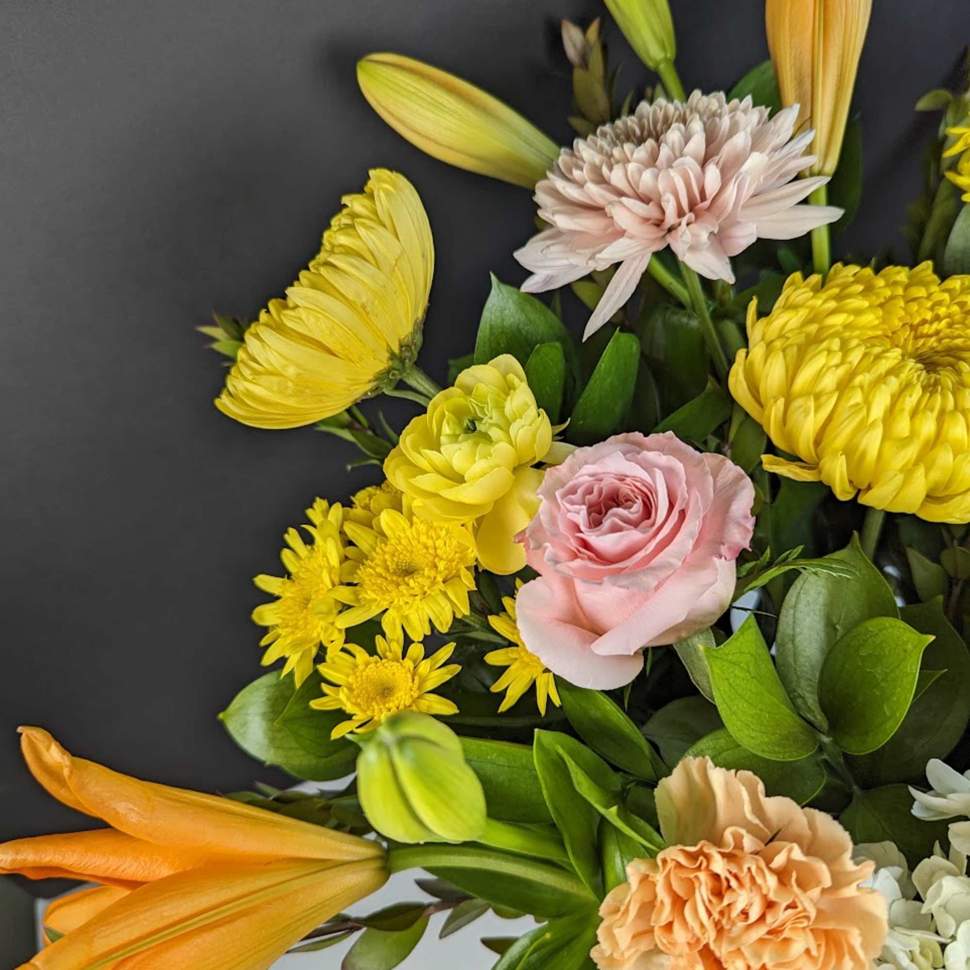 Bouquet of yellow lilies, pink roses, and chrysanthemums with green foliage