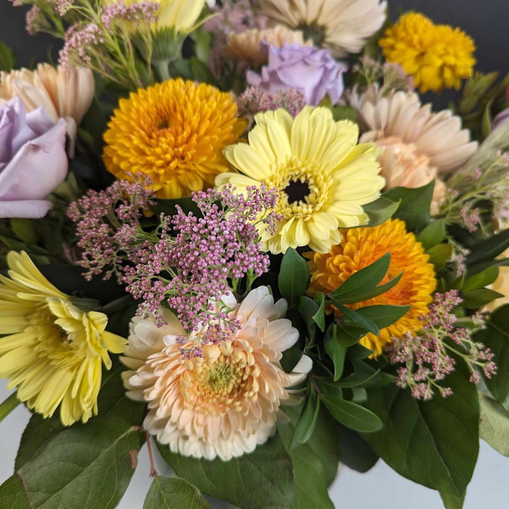 Mixed bouquet of pastel and bright daisies with purple filler flowers