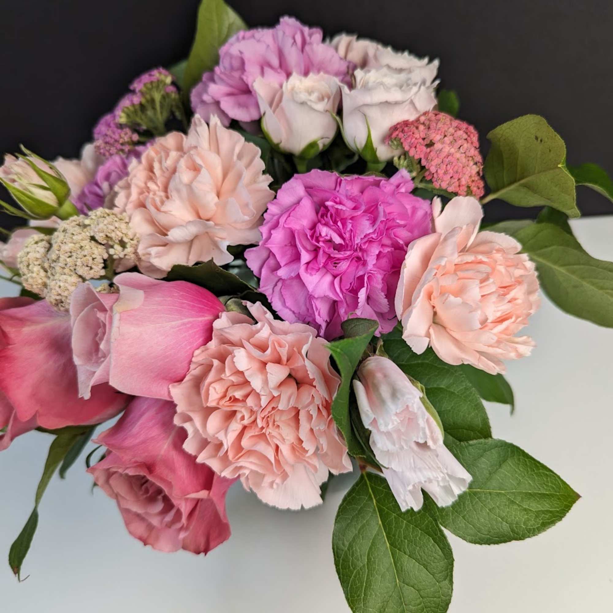 Pink and peach bouquet with roses, carnations, and small filler flowers