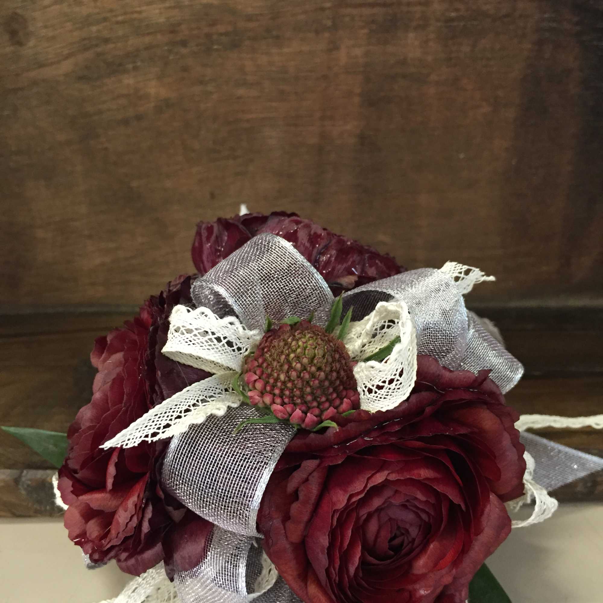 Dark red flower arrangement with ribbon and lace accents