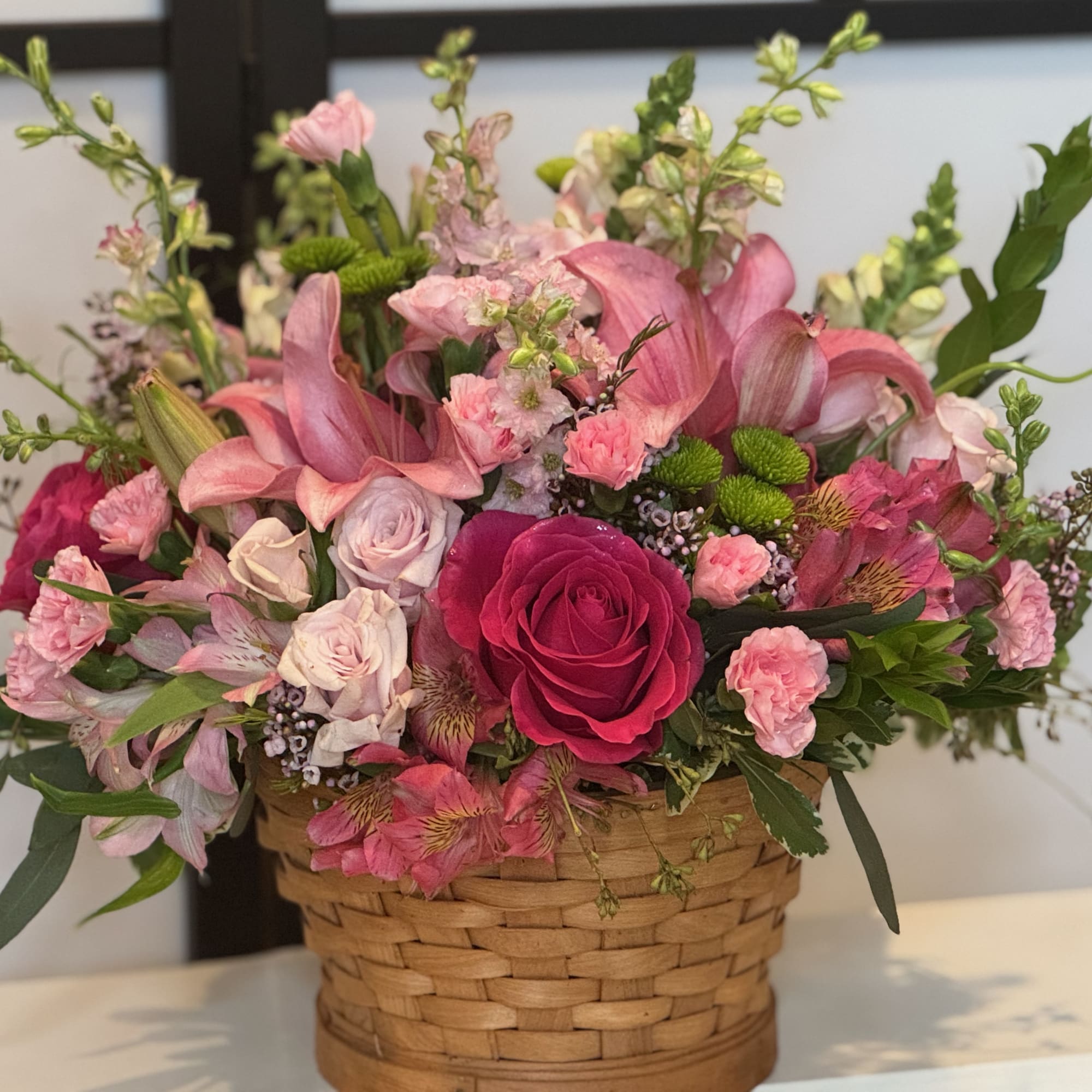 Pink and white mixed flowers arranged in a woven basket