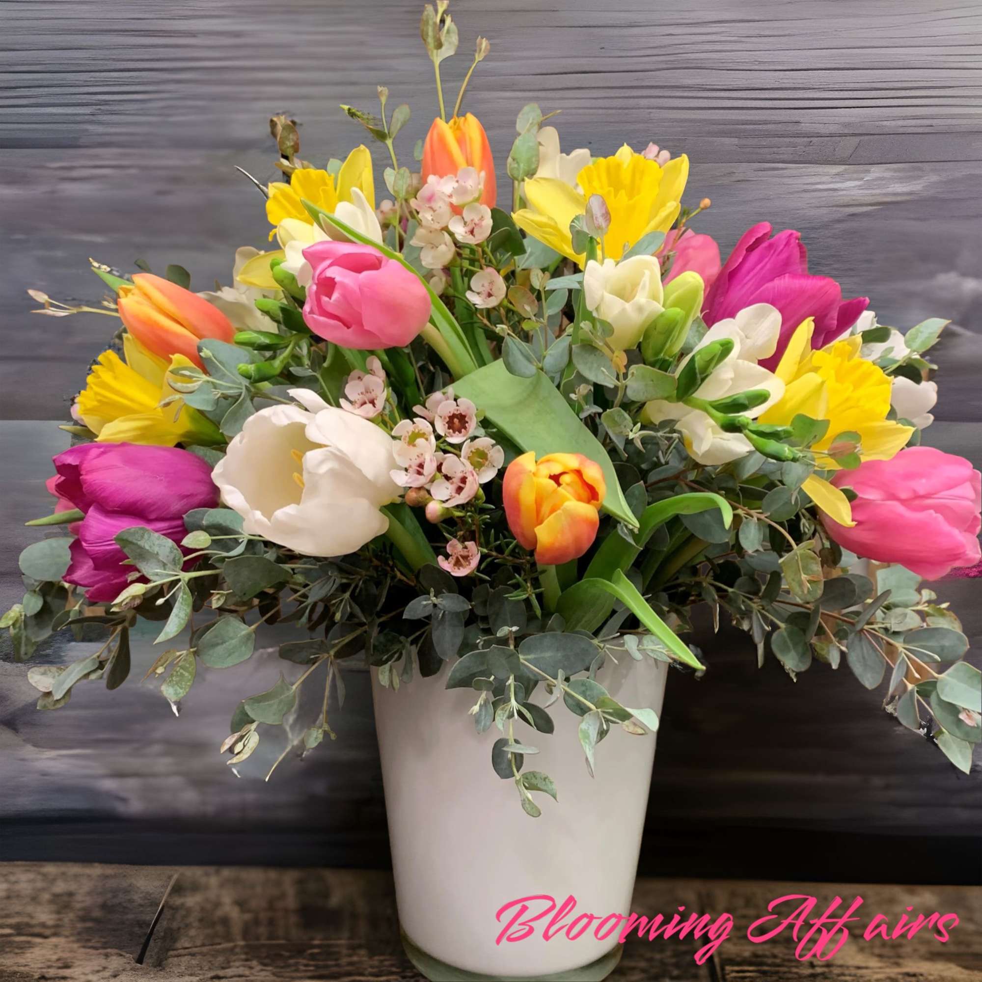 Colorful tulips and daffodils arranged in a white vase
