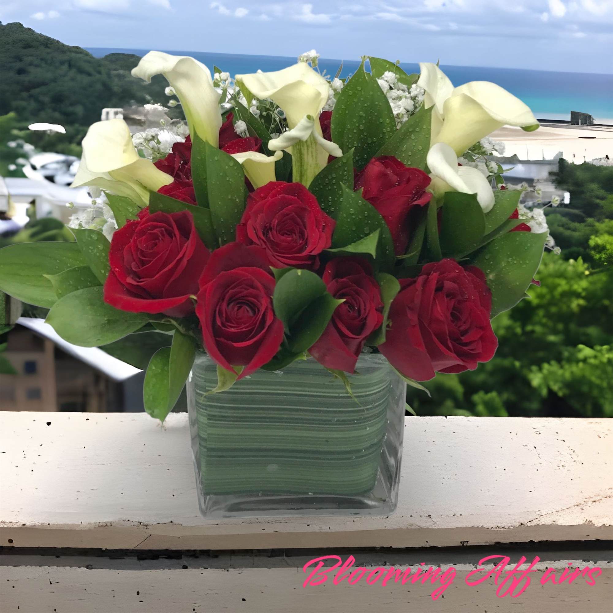 Red roses and white calla lilies in a square glass vase