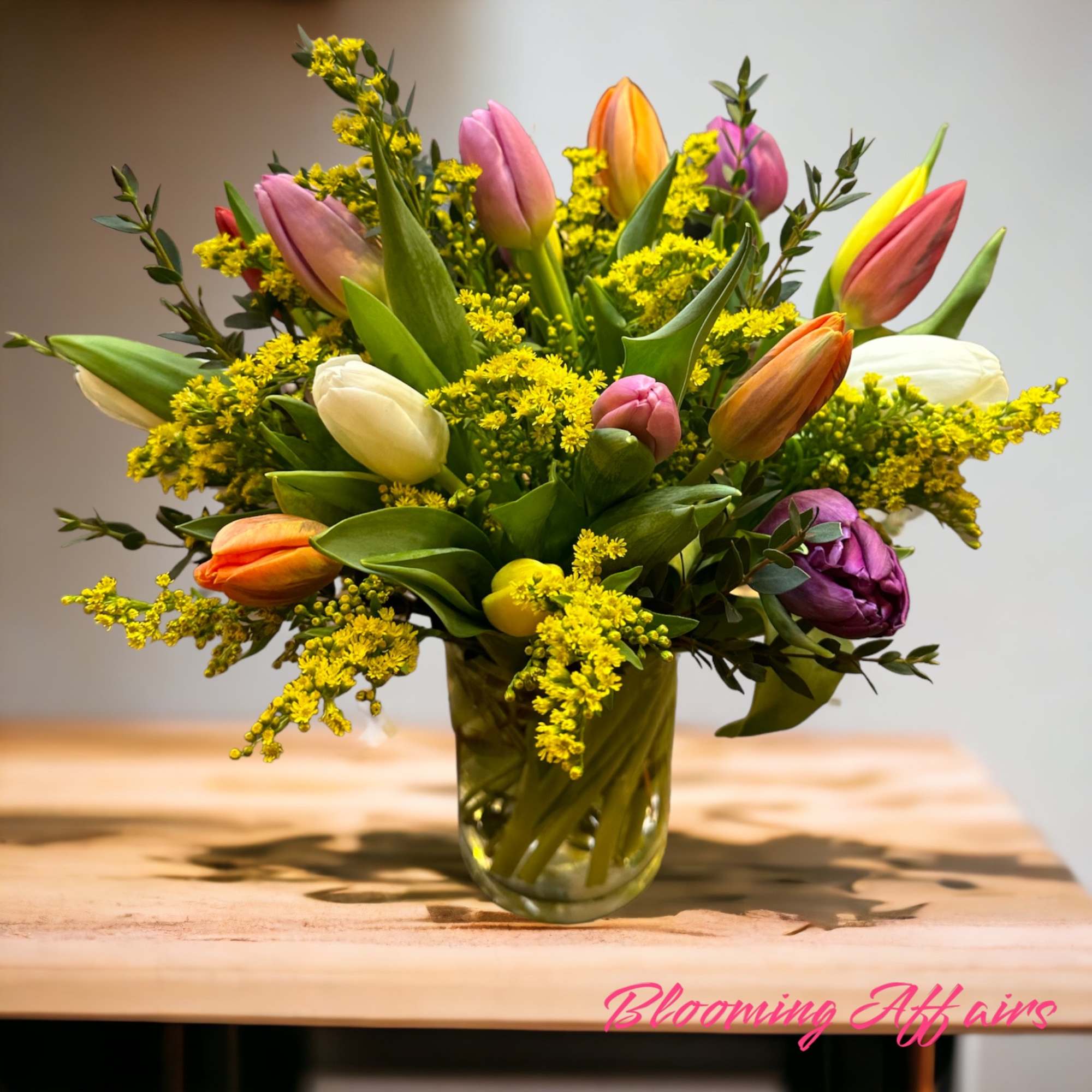 Mixed tulip bouquet in a glass vase with yellow filler flowers