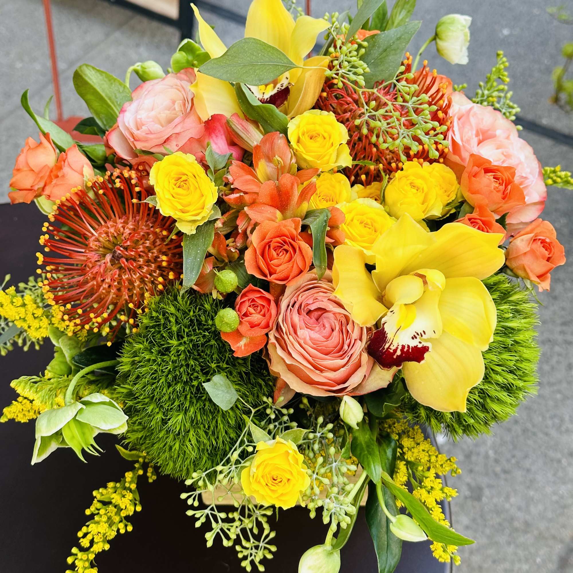 Bright bouquet of yellow orchids, roses, and orange flowers