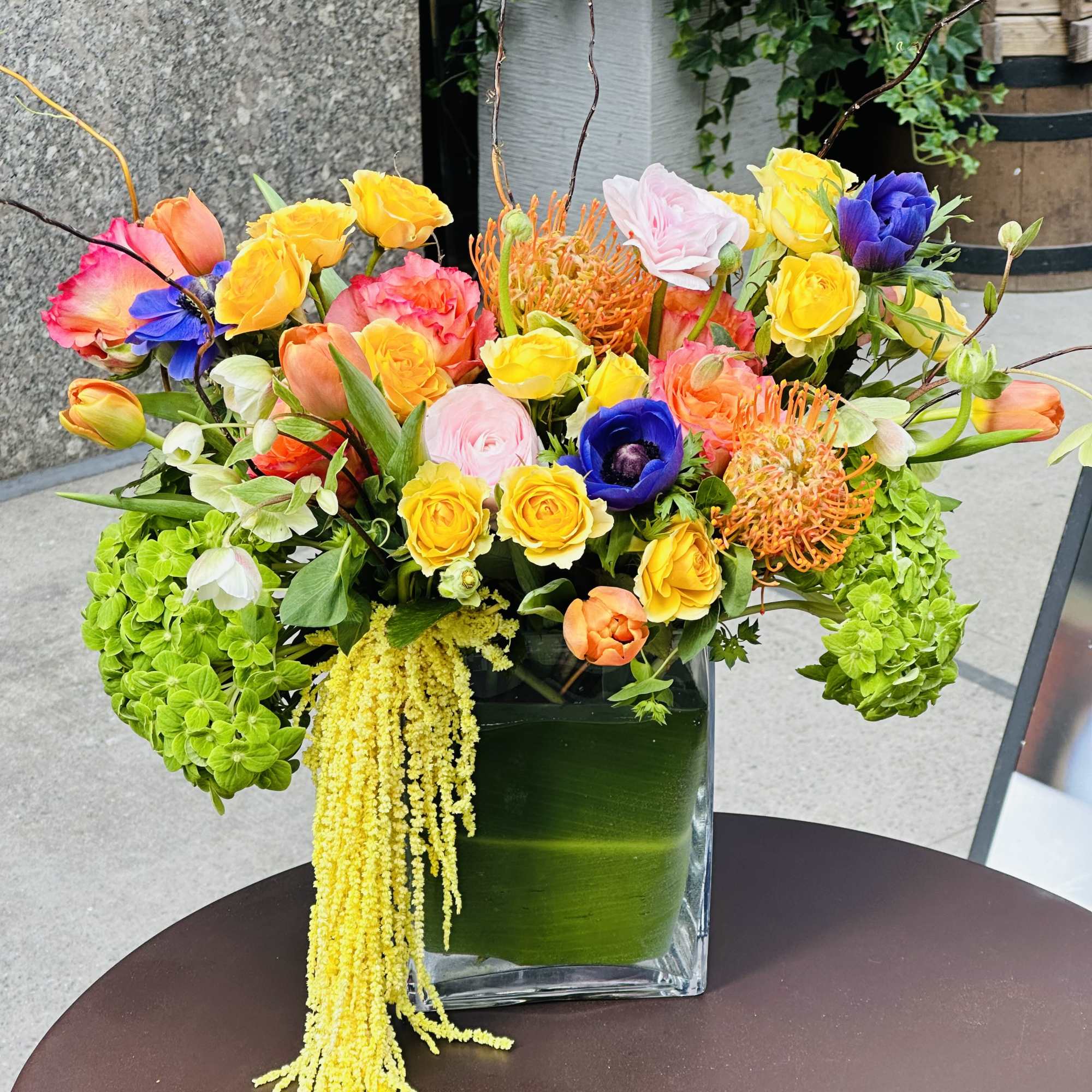 Bright mixed flower arrangement in a square glass vase