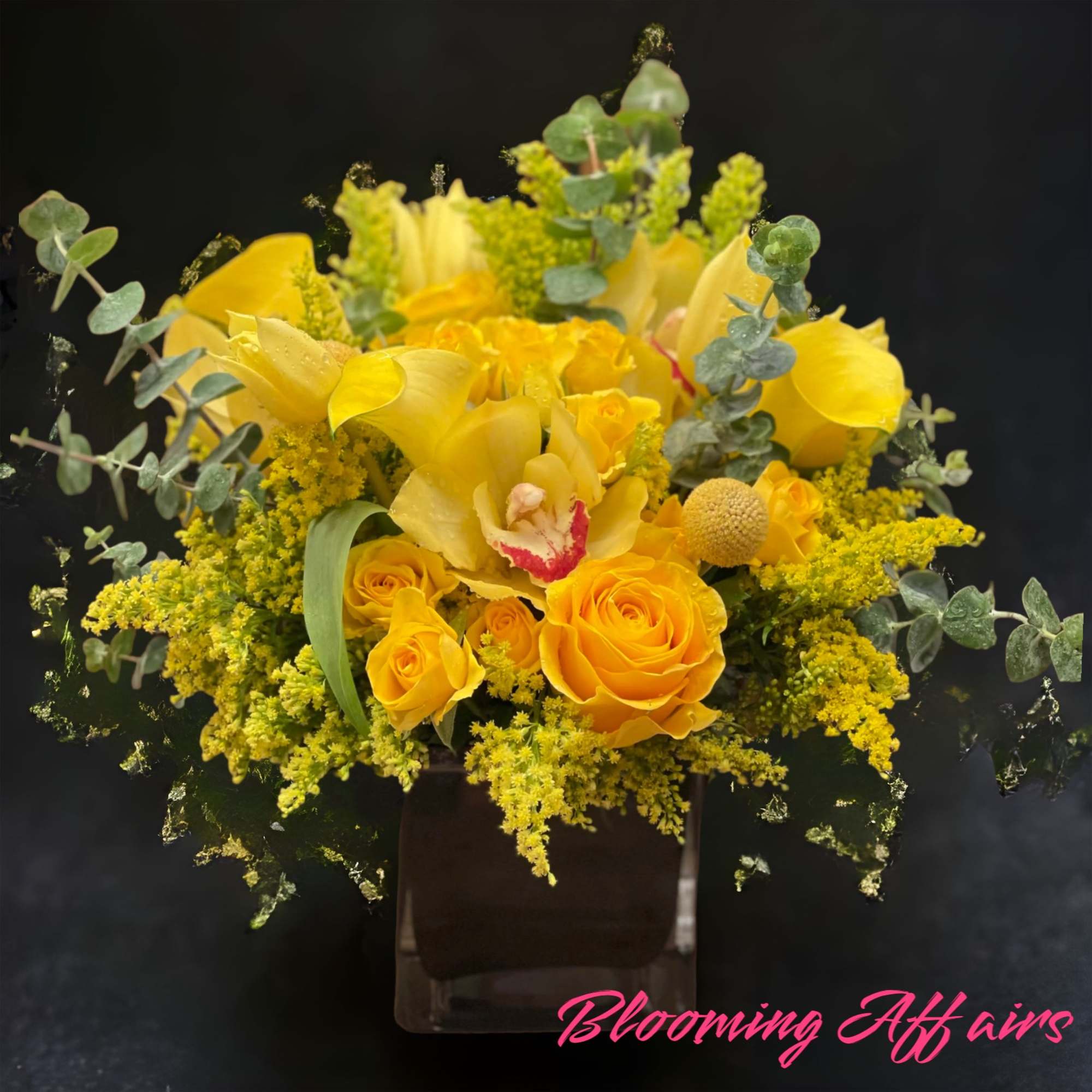 Yellow roses and calla lilies in a dark vase with eucalyptus