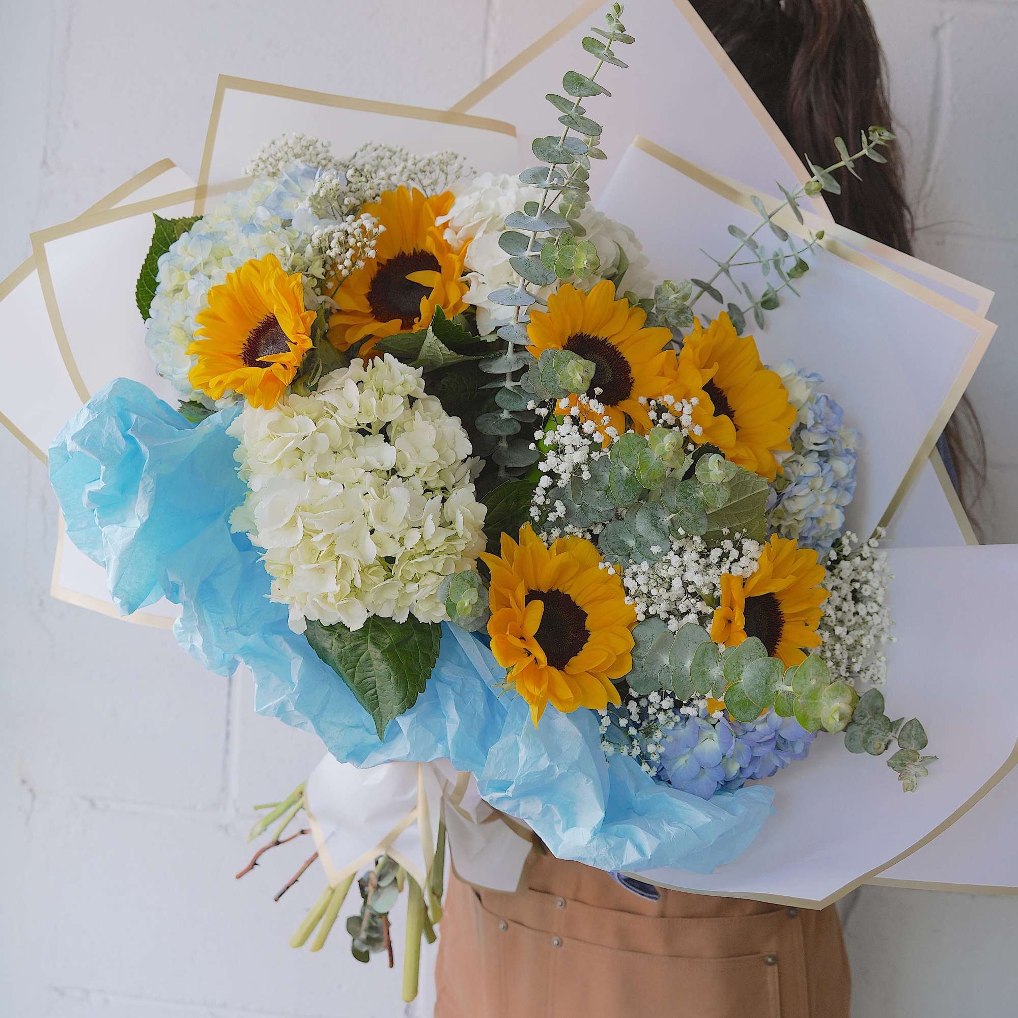 Bright sunflowers set a joyful tone in this sunflower and hydrangea bouquet-a