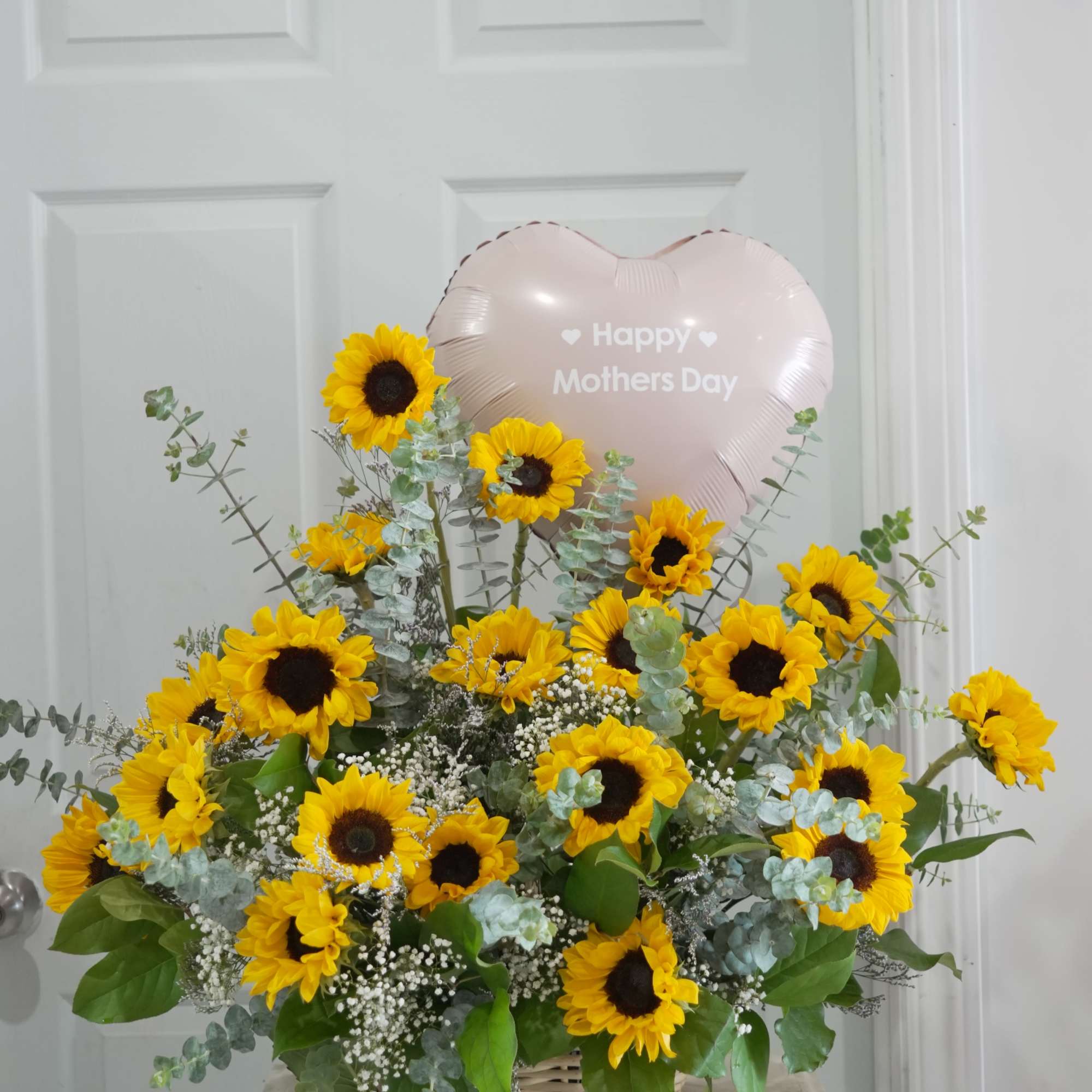 Bright yellow sunflowers with white fillers and silvery-green eucalyptus in a woven