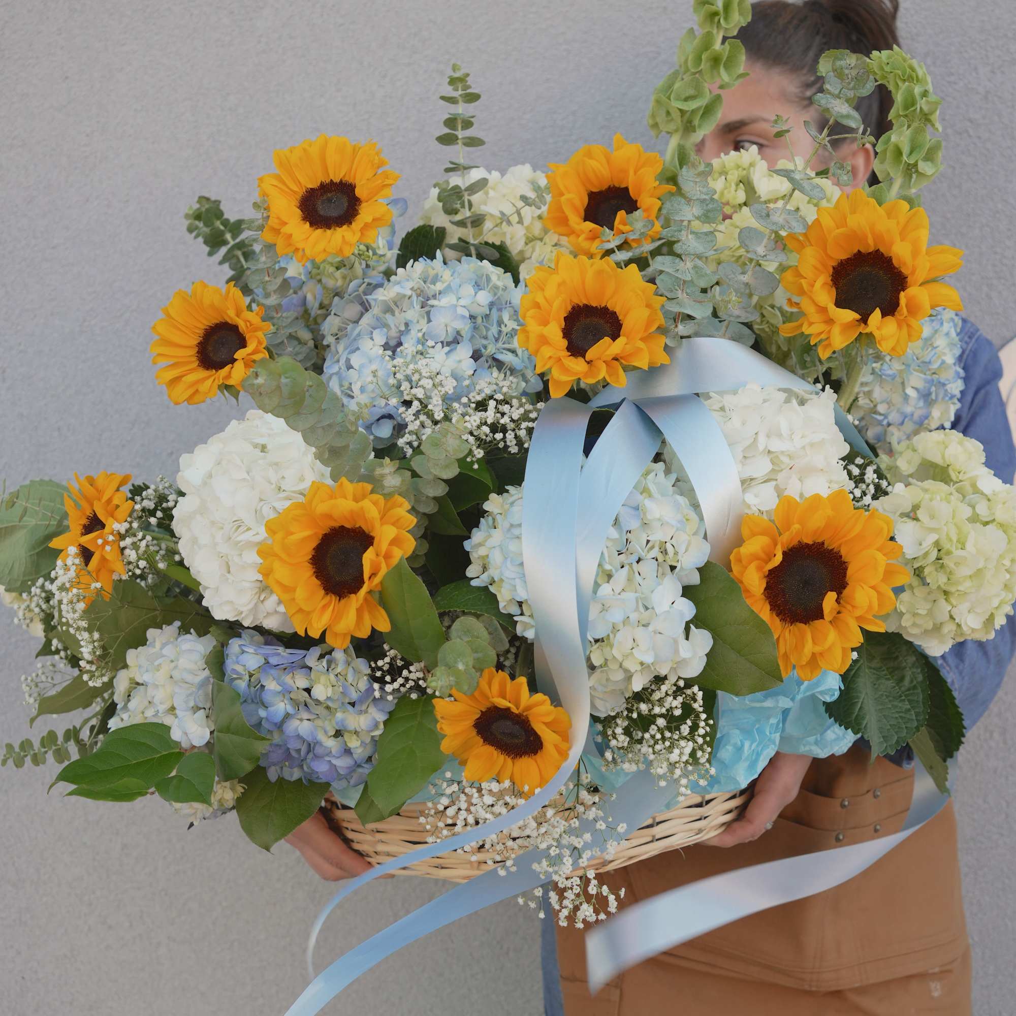 Bright yellow sunflowers take center stage in this cheerful flower arrangement, paired